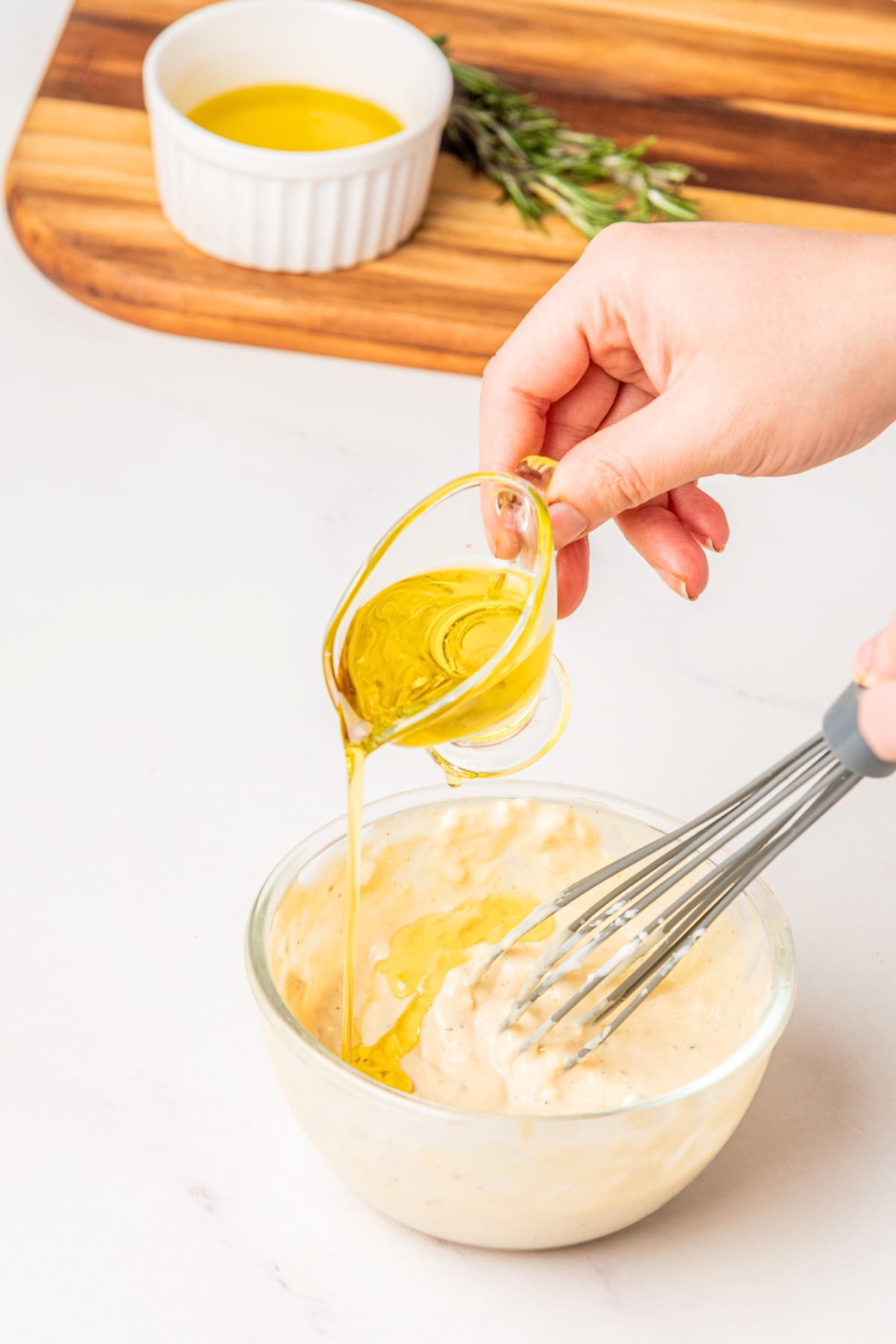 adding olive oil to caesar salad dressing