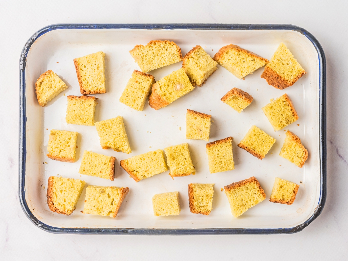 adding cubed keto bread to a white pan