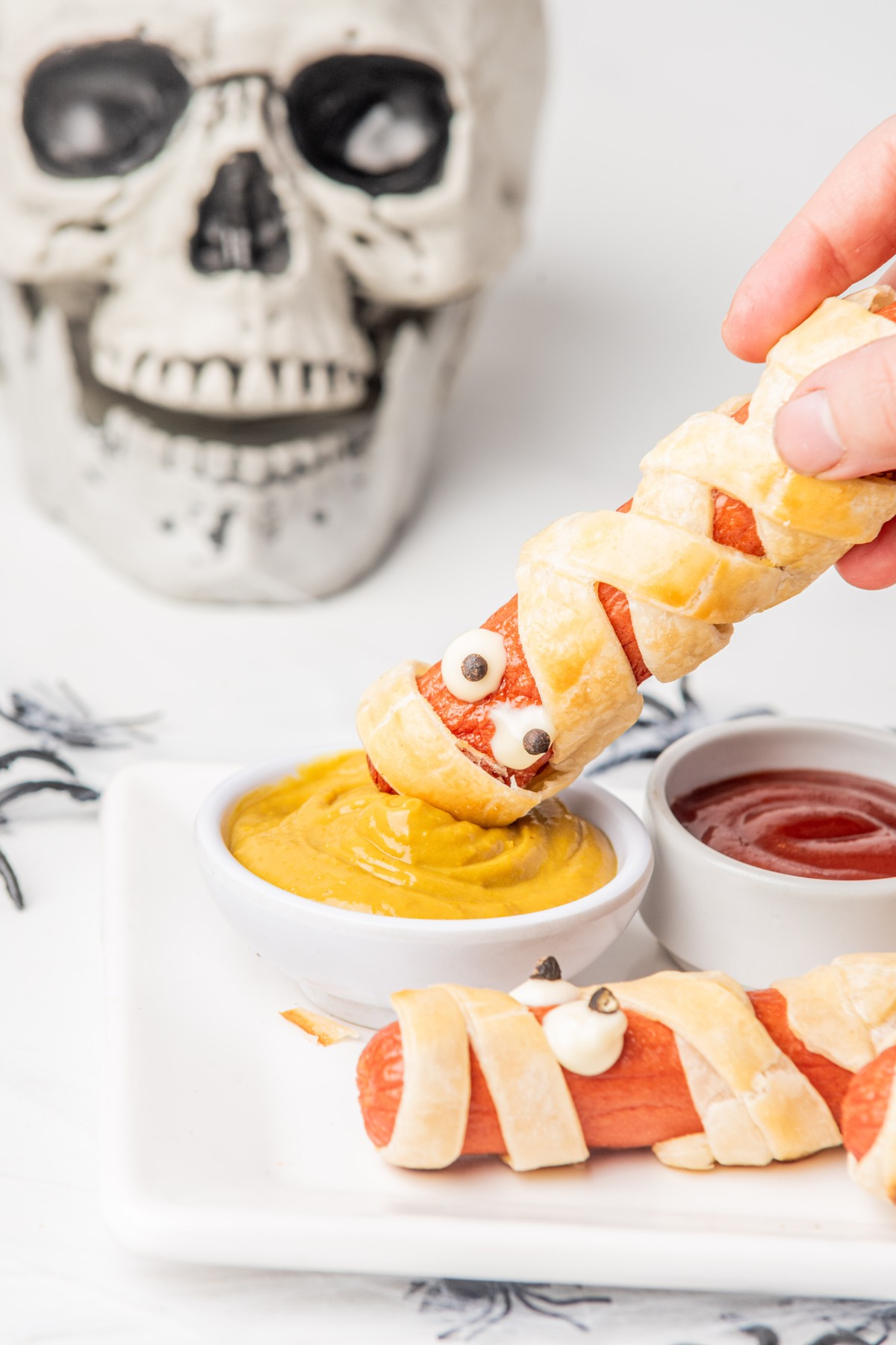 dipping hot dog mummy in mustard.