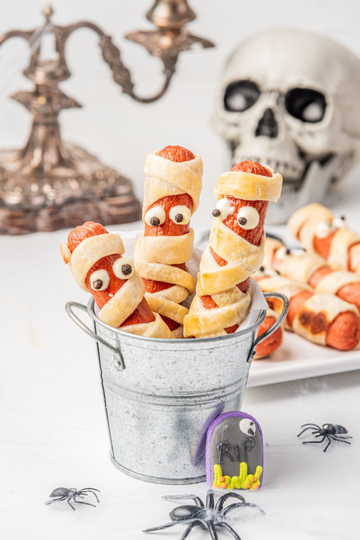 hot dog mummies in a cup with a scary skeleton. 
