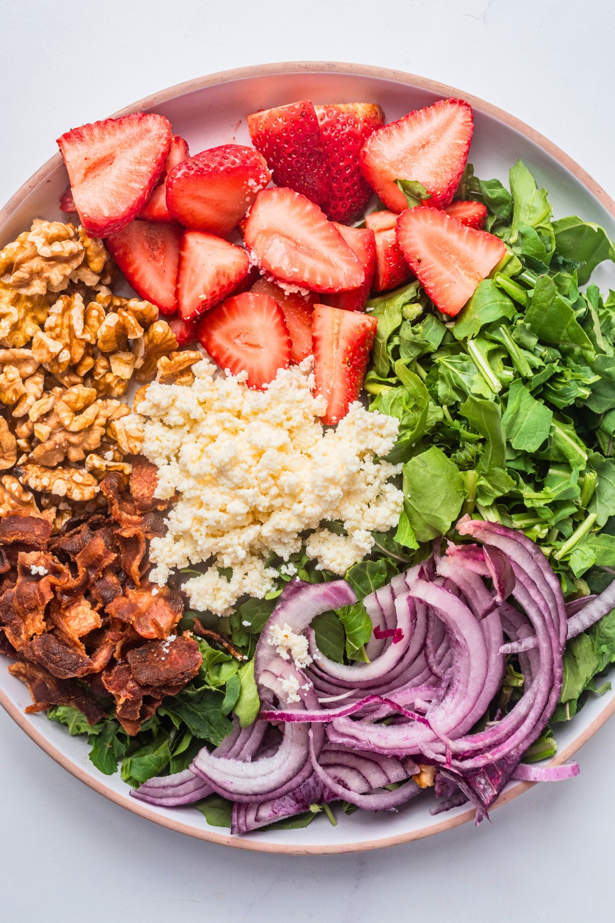 close up of strawberry salad ingredients in a bowl. 
