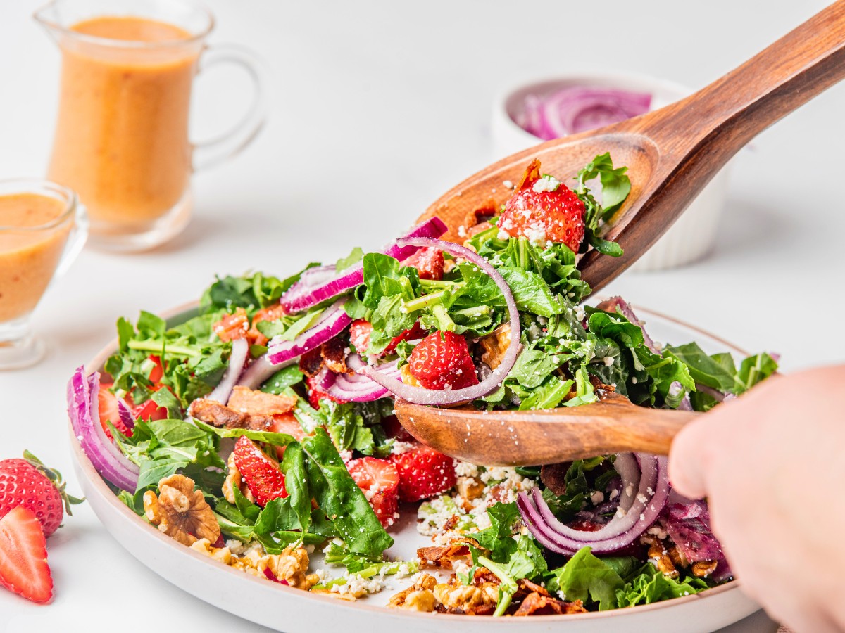 tossing goat cheese salad with salad tongs.