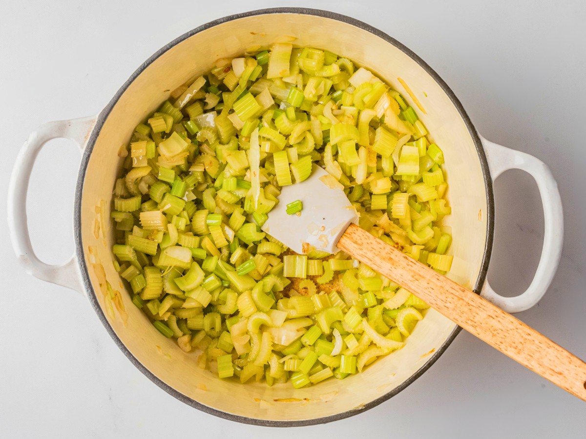 adding celery and onions in a pot
