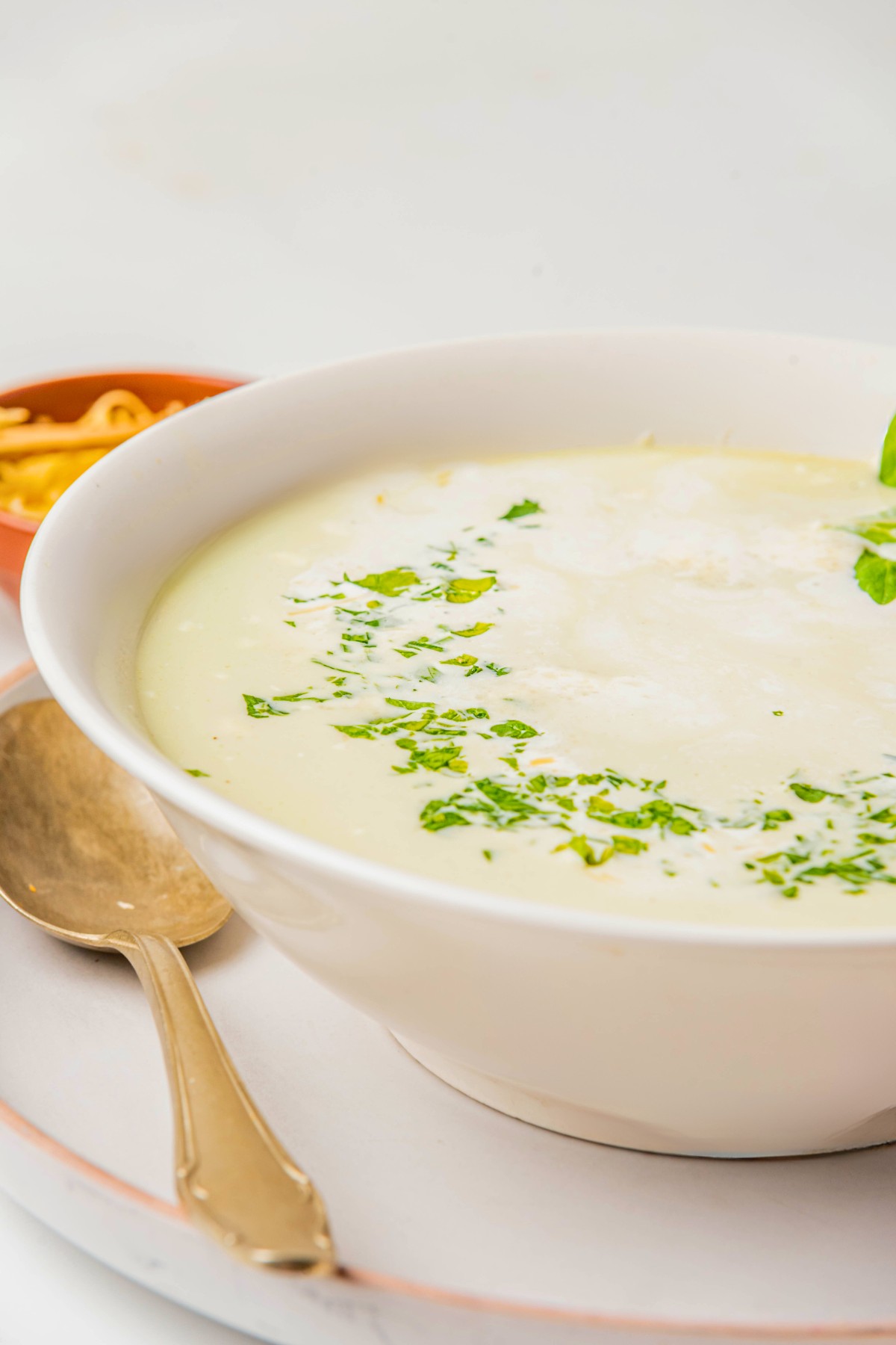 side view of celery soup with fresh herbs and celery leaves. 