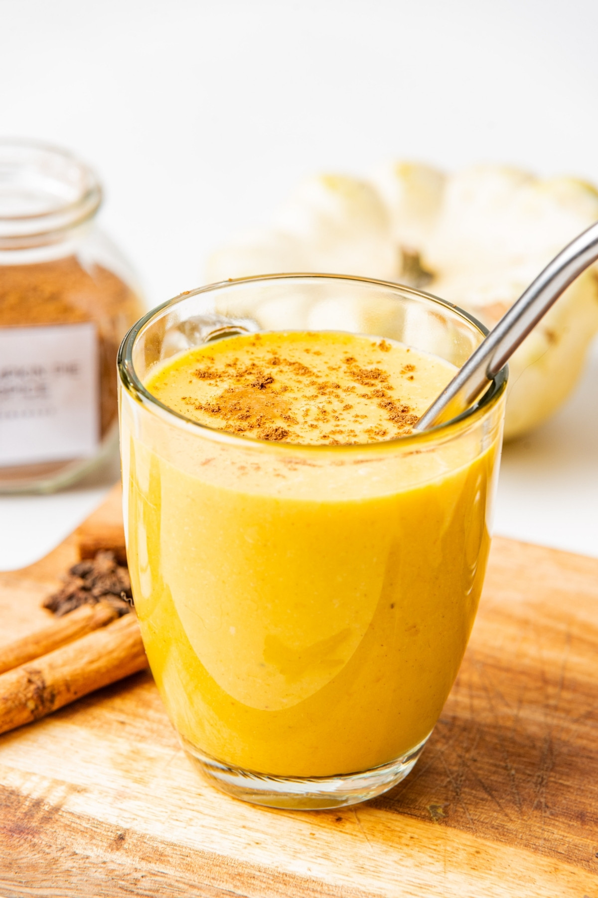 close up of pumpkin smoothie in a glass with a straw.