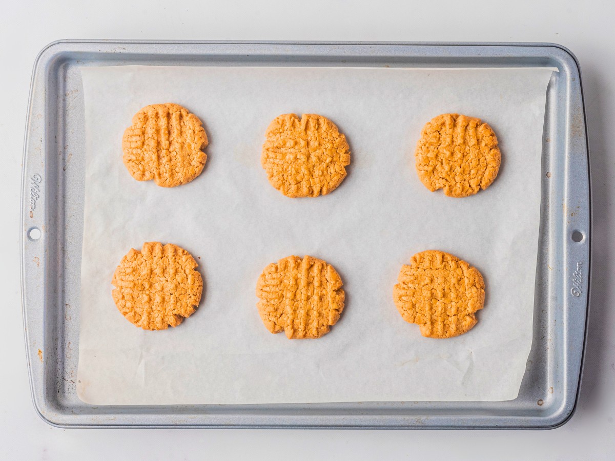 baked peanut butter cookies on a lined baking sheet. 