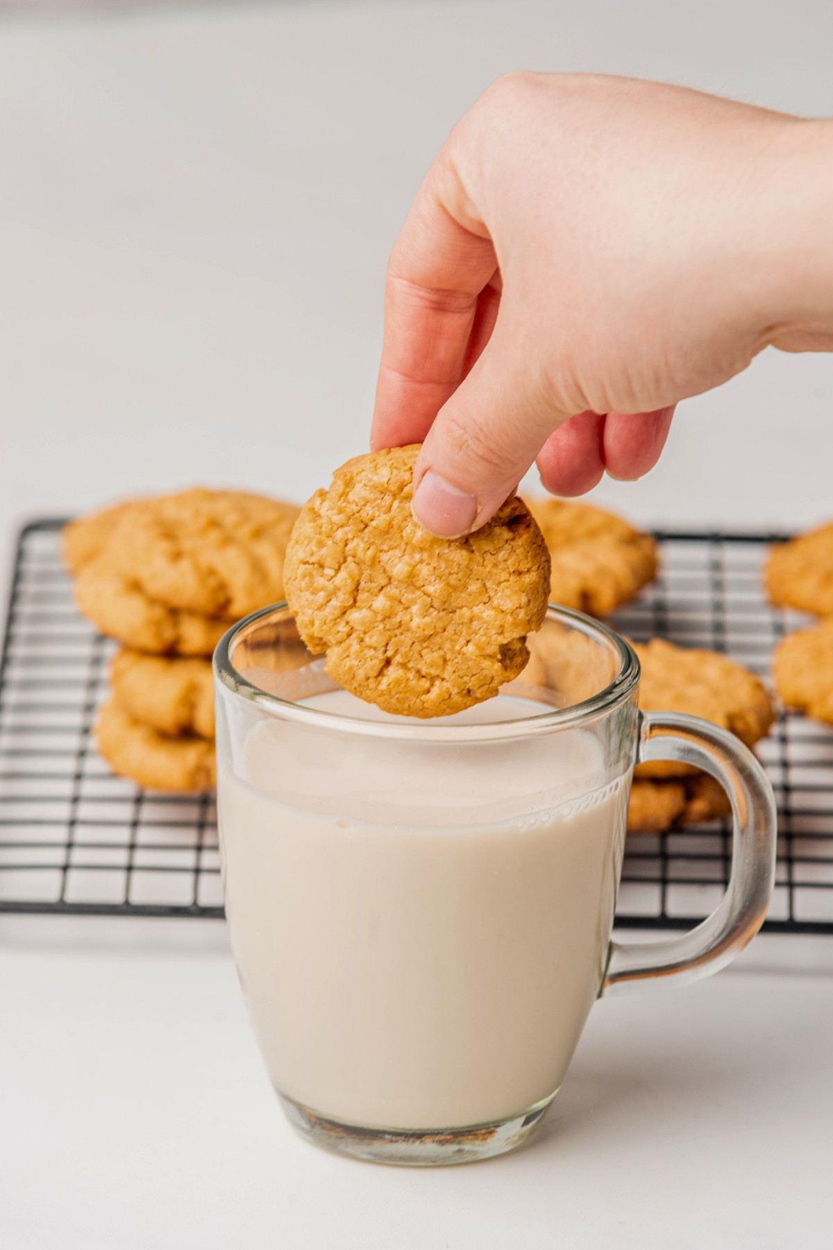 peanut cookies hovering over glass of milk. 