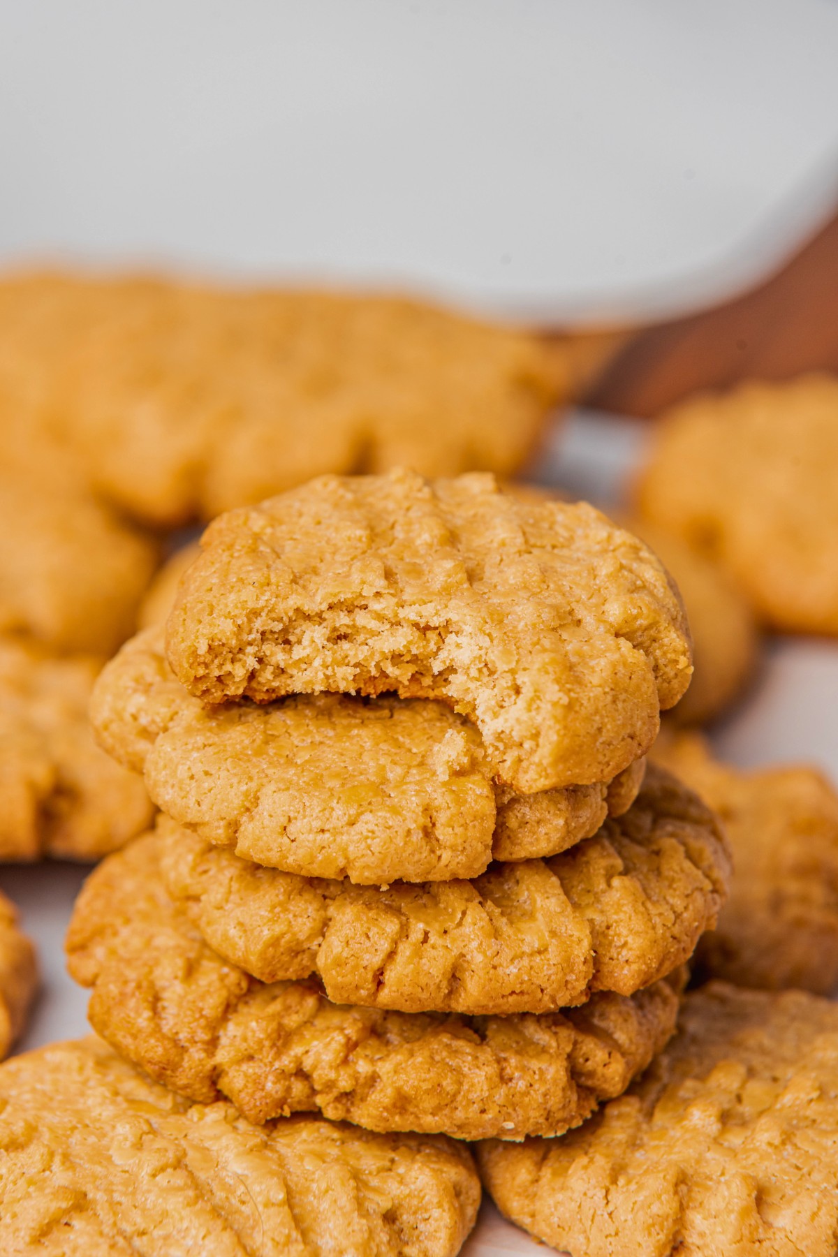 a stack of peanut butter cookies with a bite taken out of one on top. 