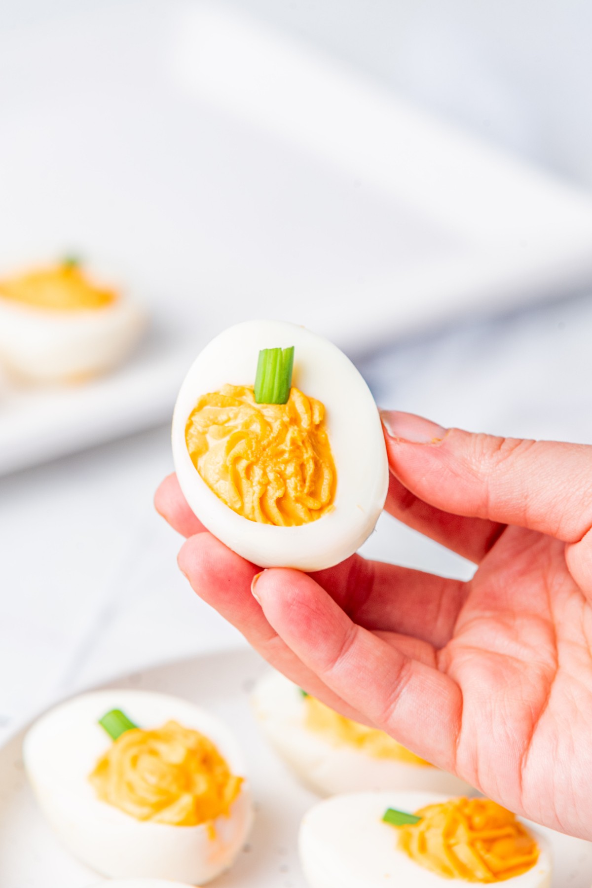 holding up a pumpkin shaped deviled egg. 