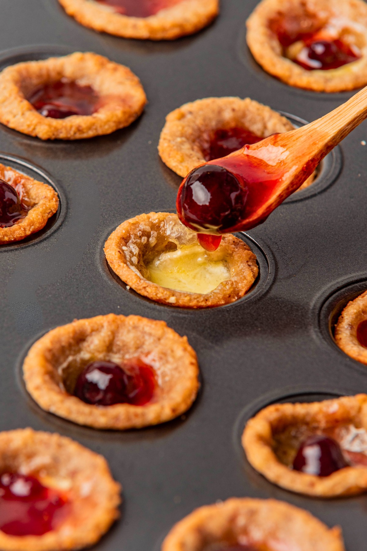spooning a dollop of cranberry sauce into Brie cups