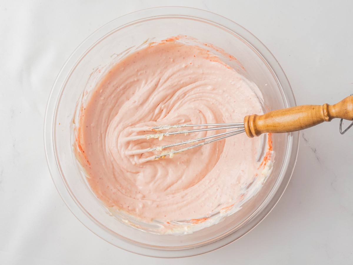 strawberry cream cheese frosting being mixed in a bowl