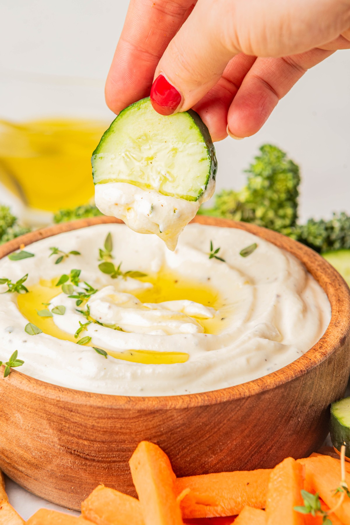 dipping cucumber into cheesy ricotta appetizer