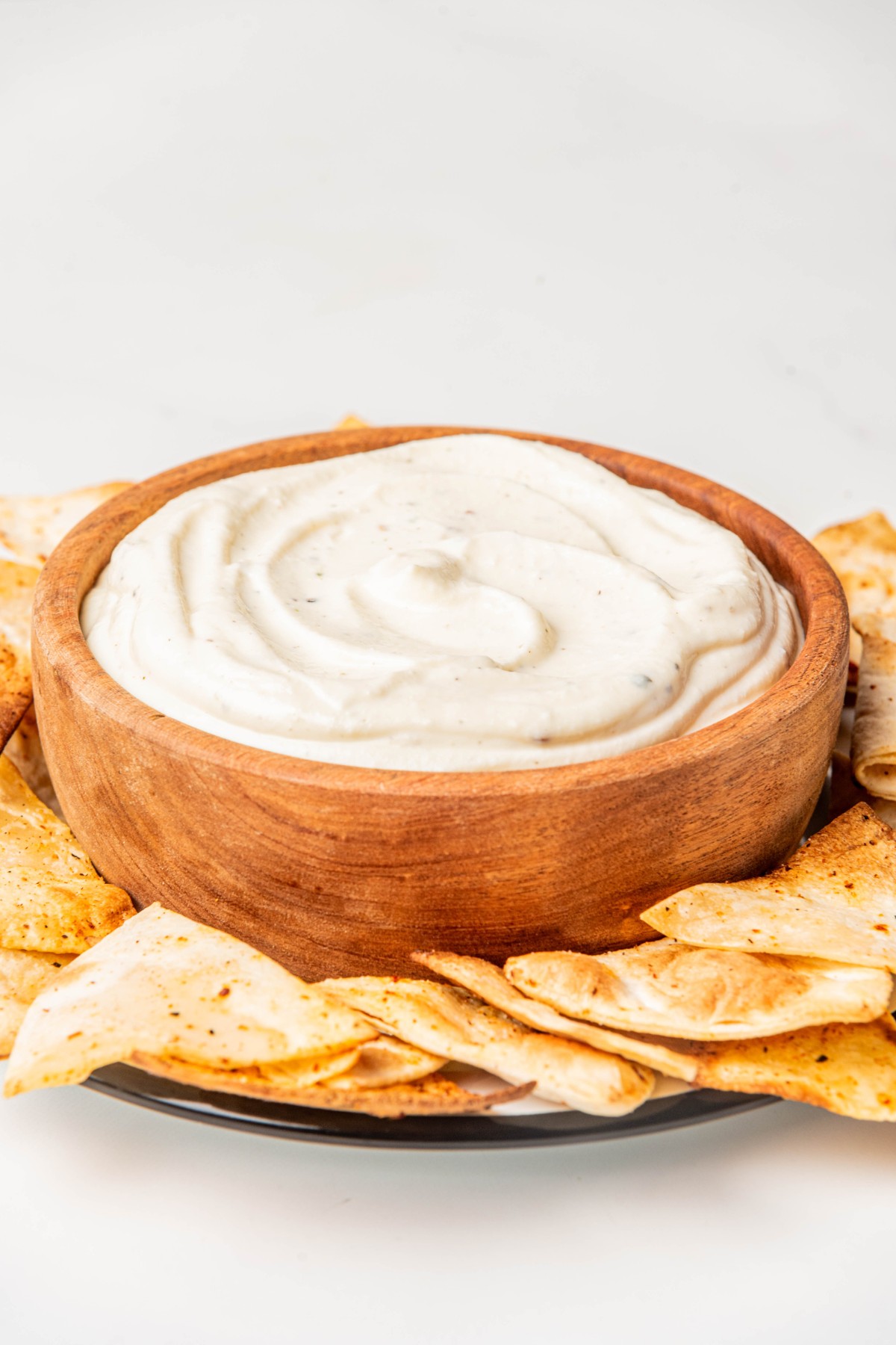 adding whipped ricotta dip to a wooden bowl and served with keto chips. 