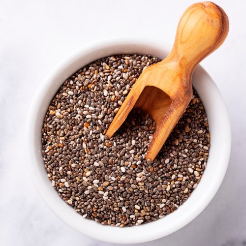 glass bowl of fresh chia seeds with wooden spoon