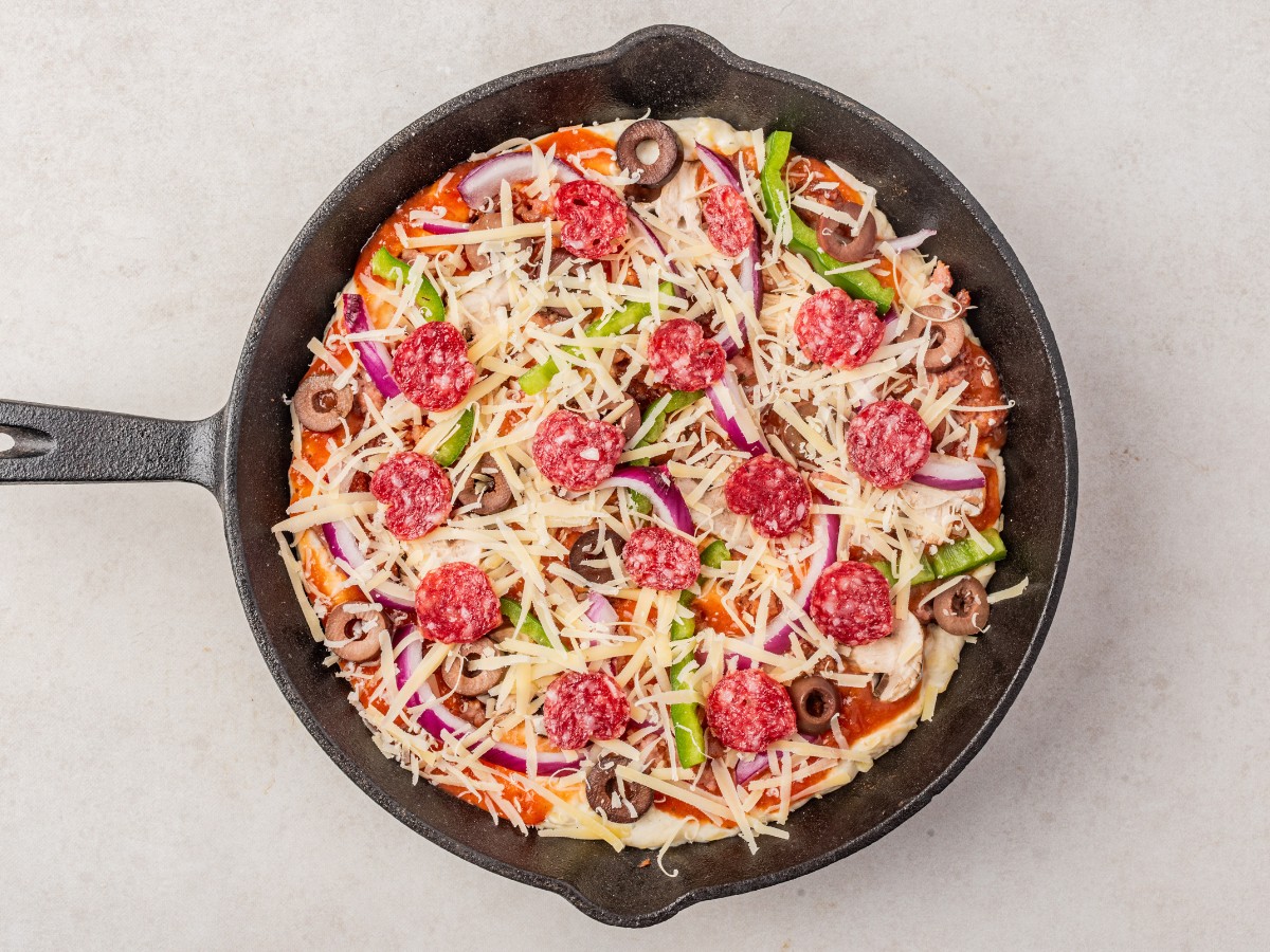 سربار پیتزای پخته نشده را در یک تابه چدنی با تکه های فلفلی اضافه کنید.