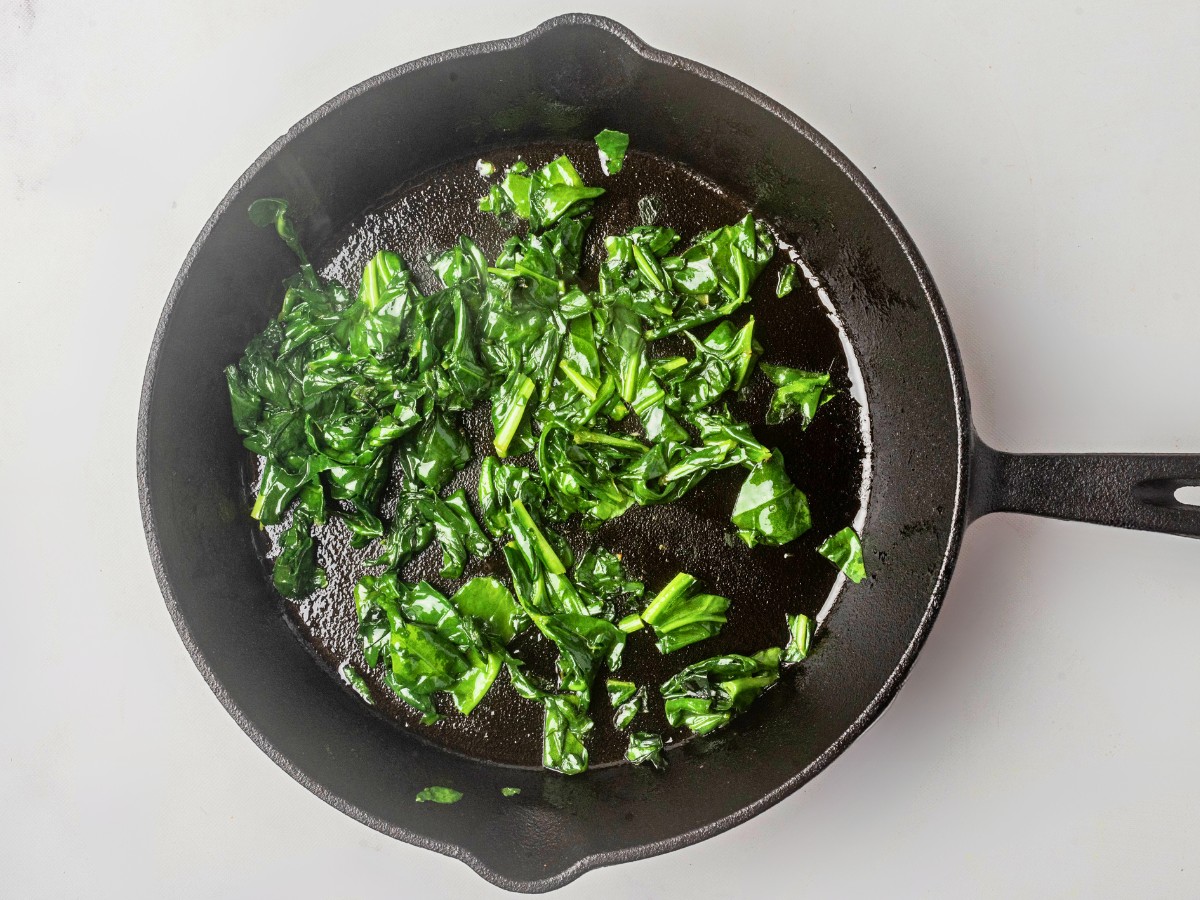 cooking spinach in a cast iron pan.