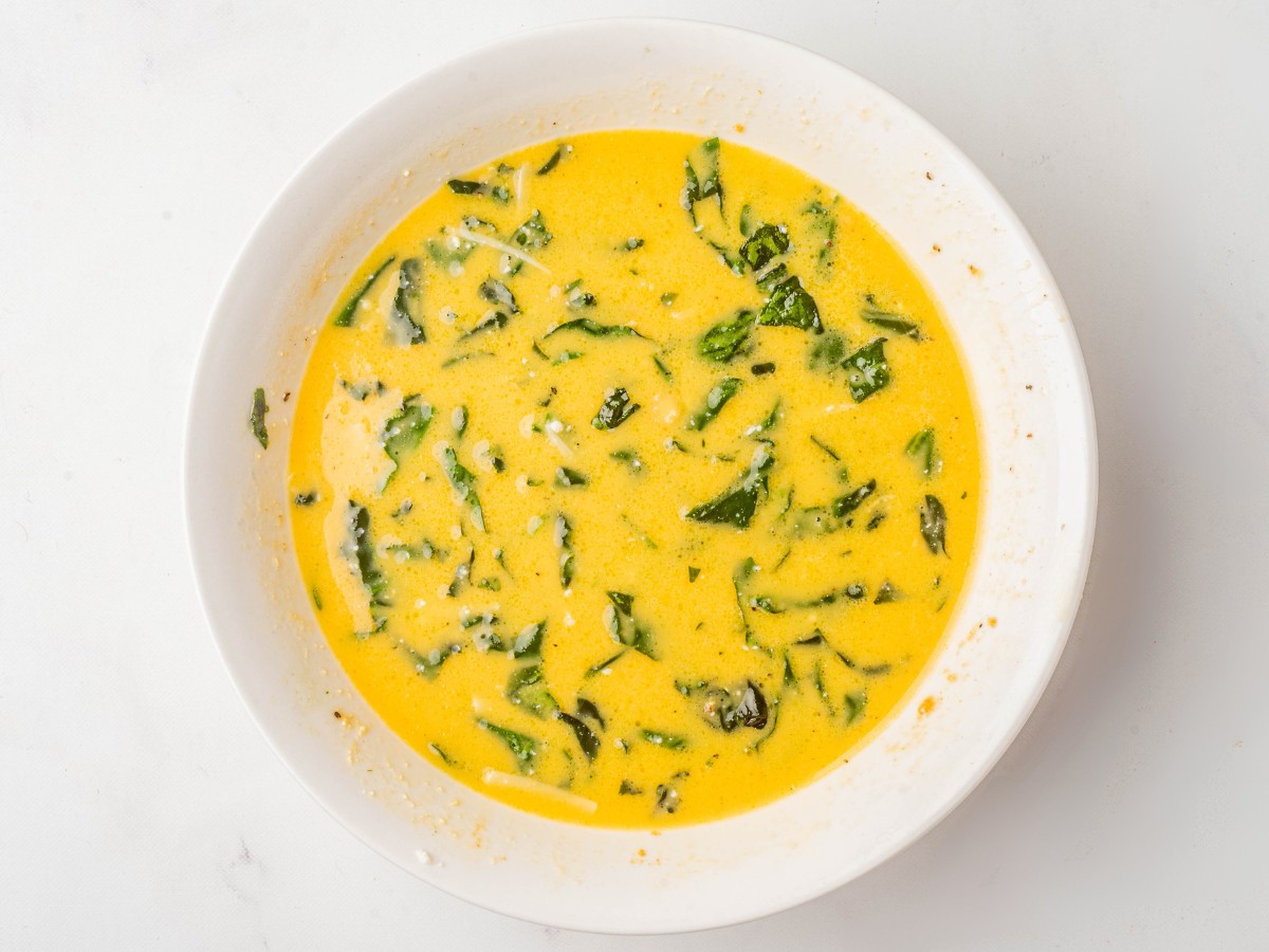 mixing together eggs and spinach for frittata