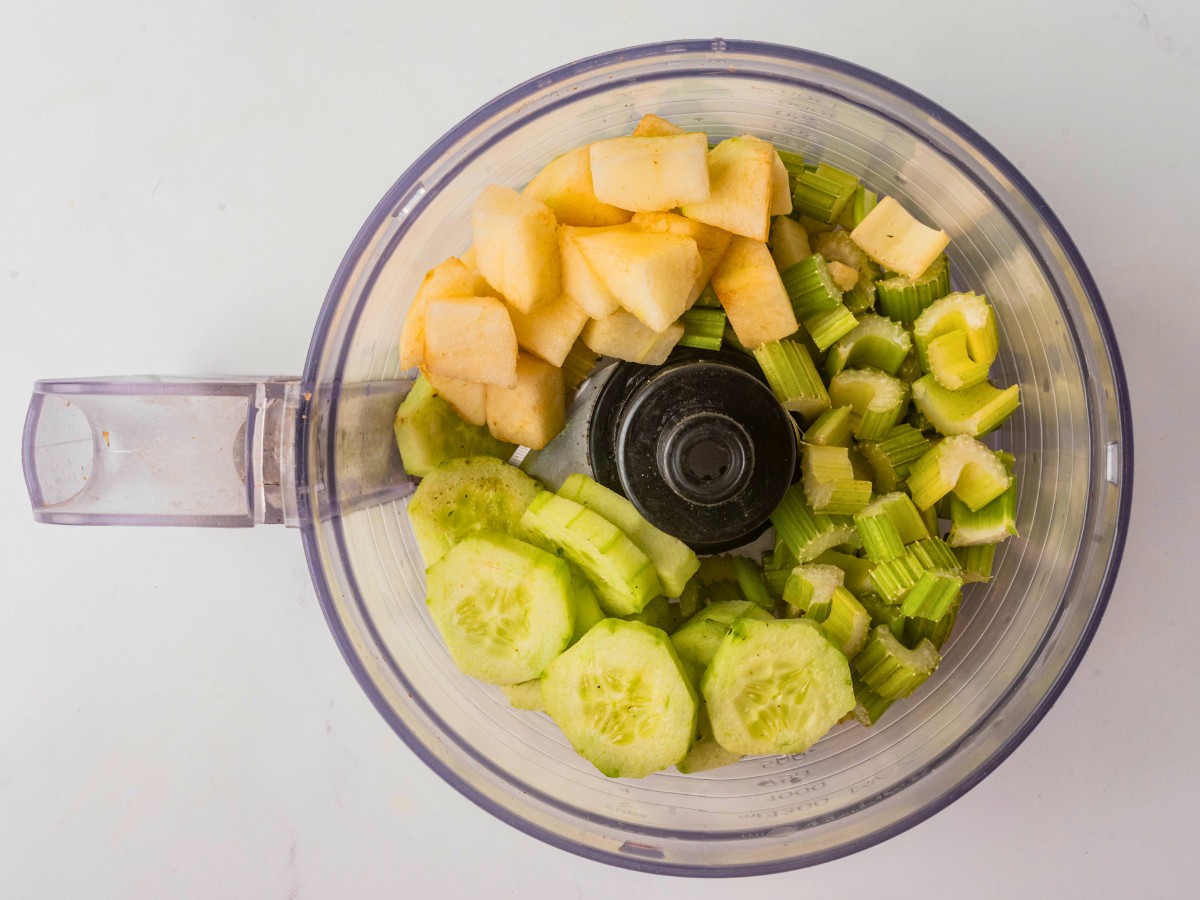 adding chopped veggies and fruit to a food  processor