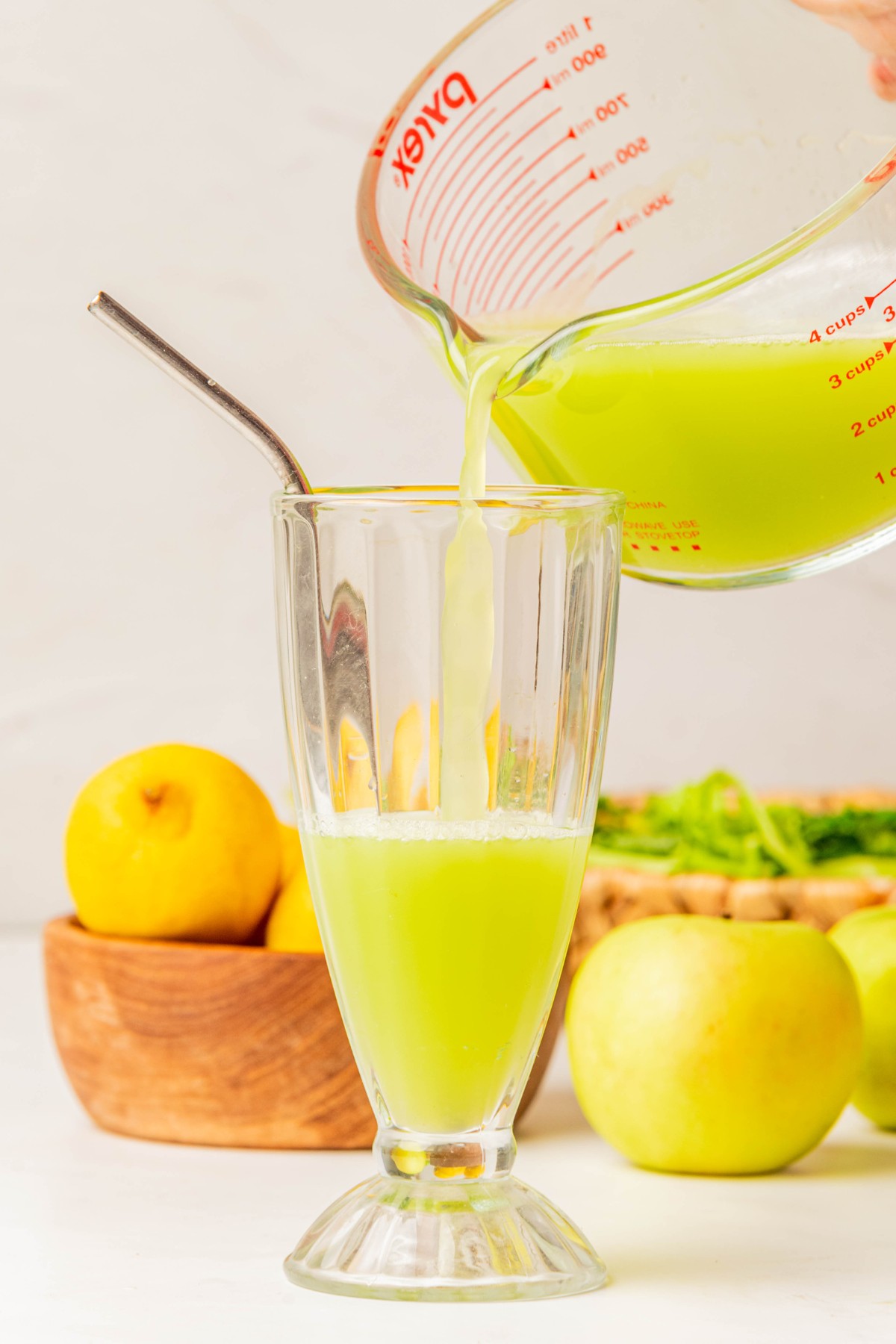 pouring homemade green juice into glass cup