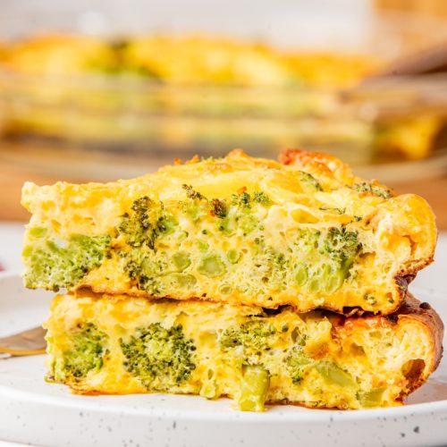 close-up shot of two slices of crustless broccoli cheddar quiche stacked on top of each other on a white plate.
