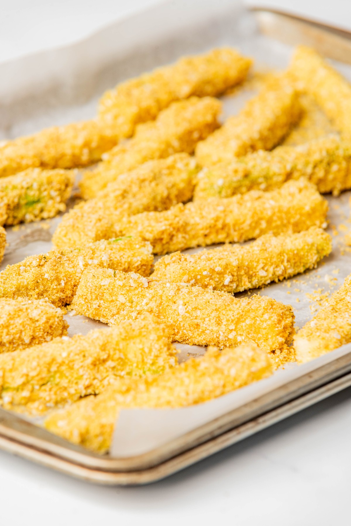 breaded zucchini sticks on a baking sheet before going in the oven.
