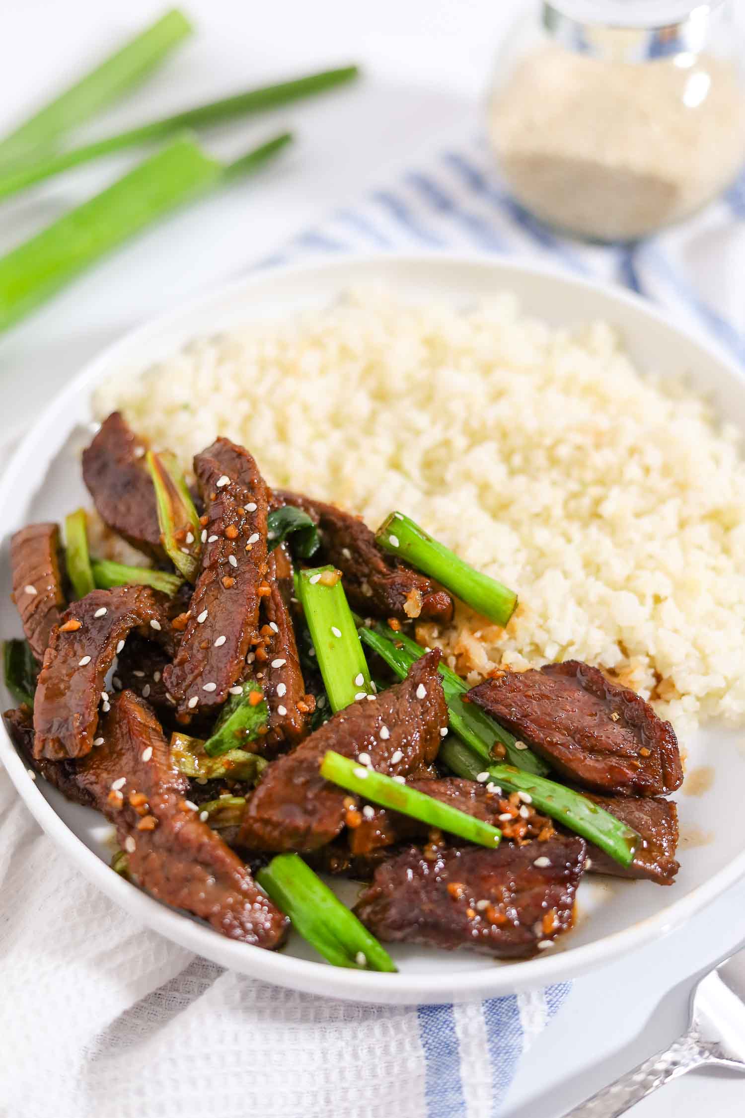 mongolian beef with cauliflower rice on a white plate.