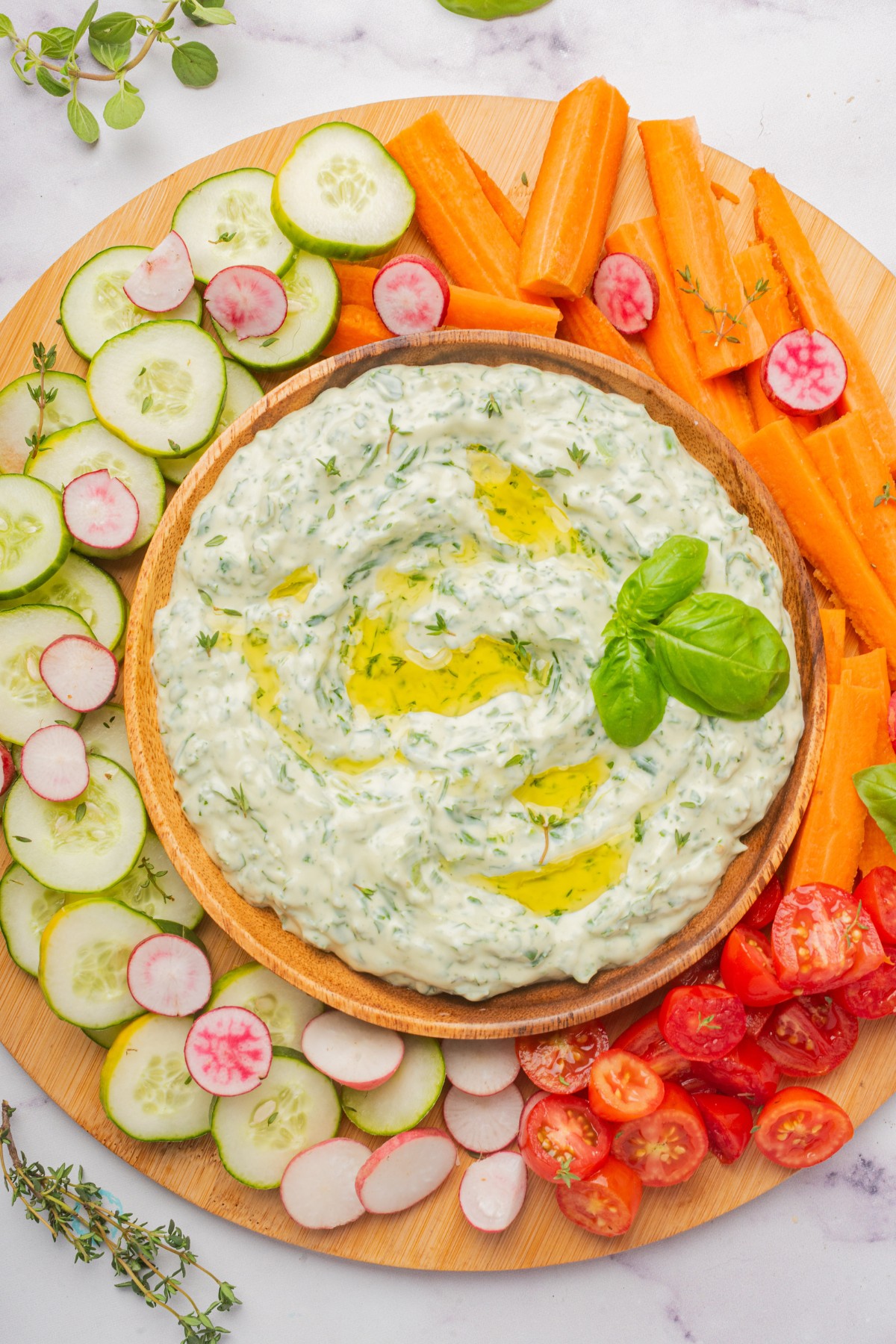 green goddess dip in a bowl served with carrots, cucumbers and radishes 