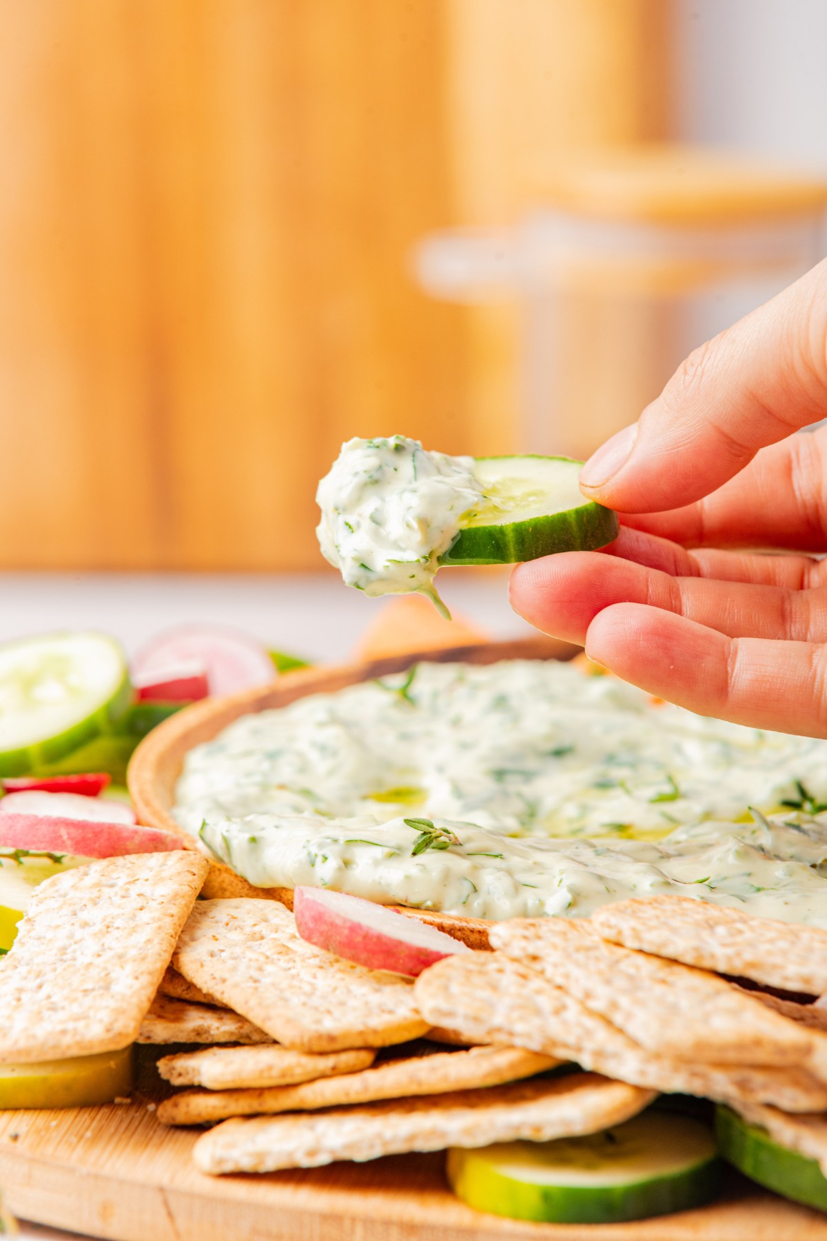 using a cucumber slice to scoop up green goddess dressing dip 