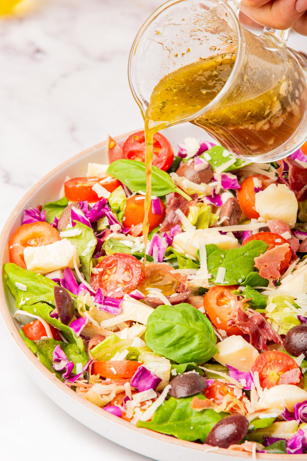 drizzling red wine dressing over chopped italian salad