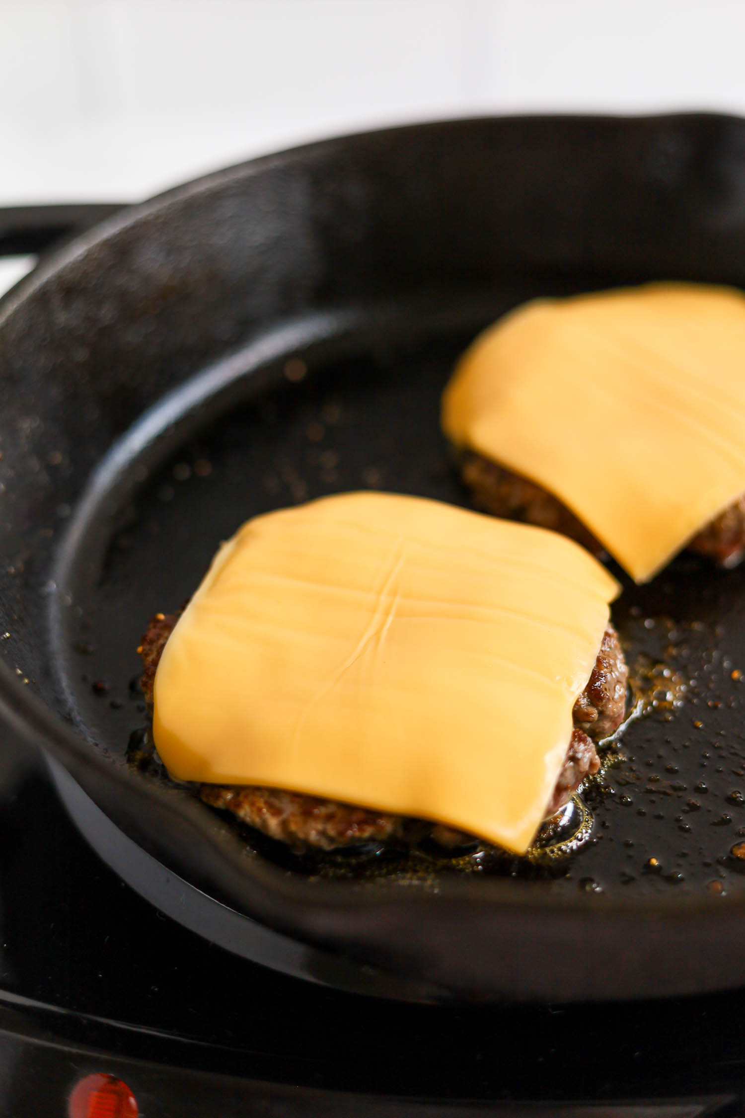 adding a cheese slice over grilled hamburger 