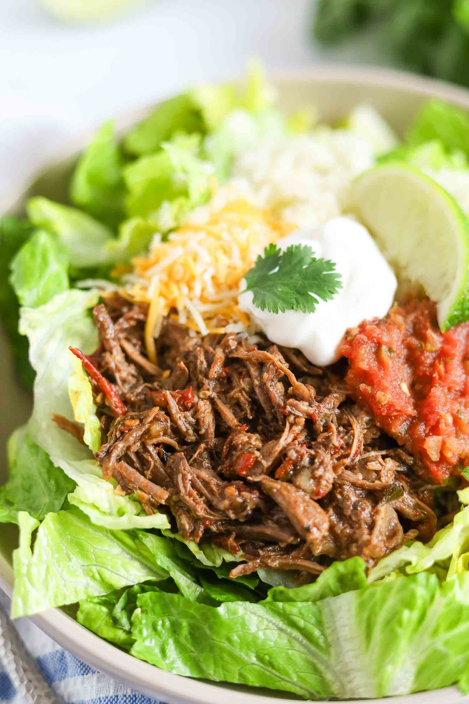barbacoa beef taco bowl with lettuce, cheese, sour cream and salsa. 