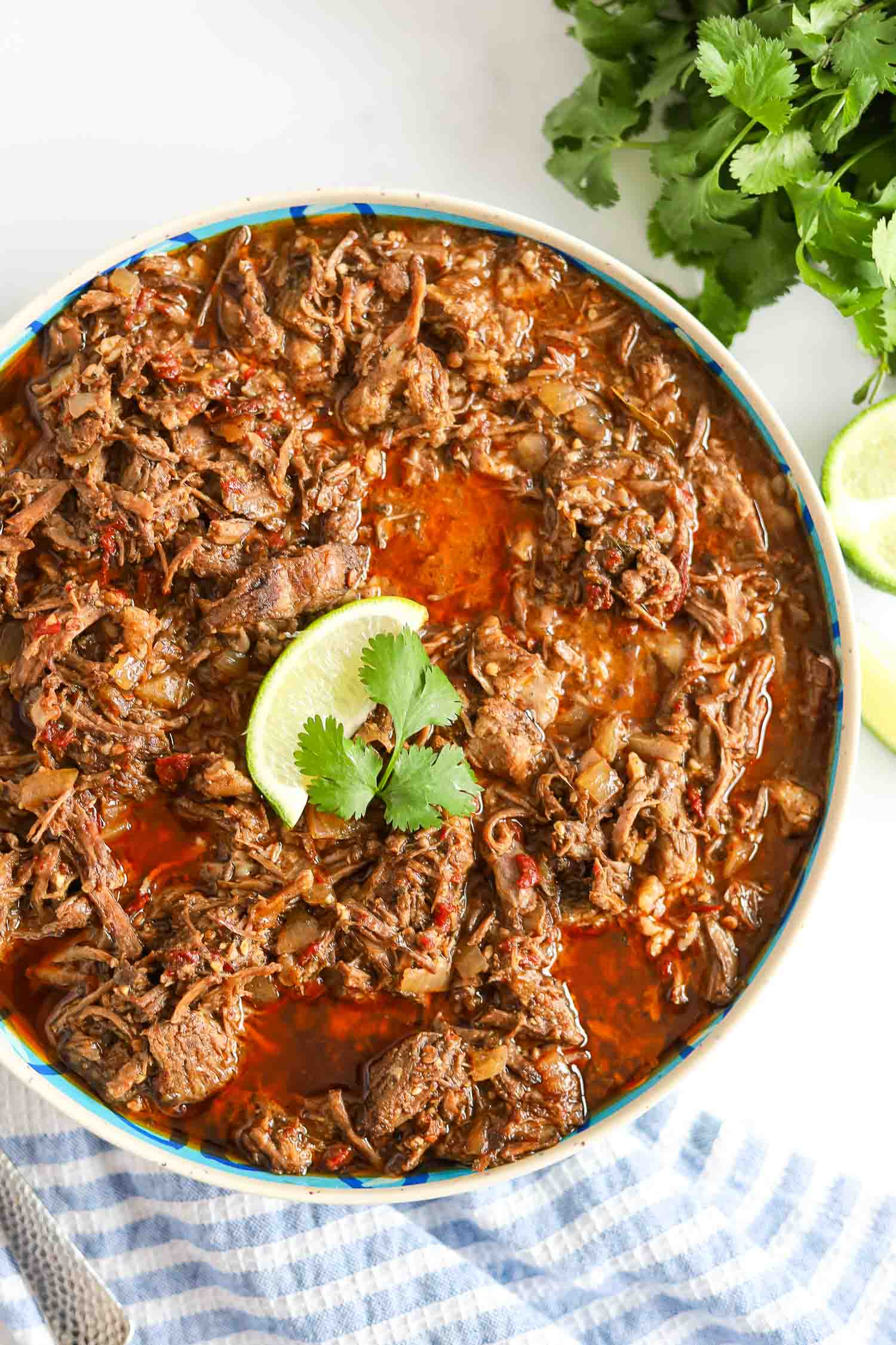 shredded beef barbacoa in a bowl with limes