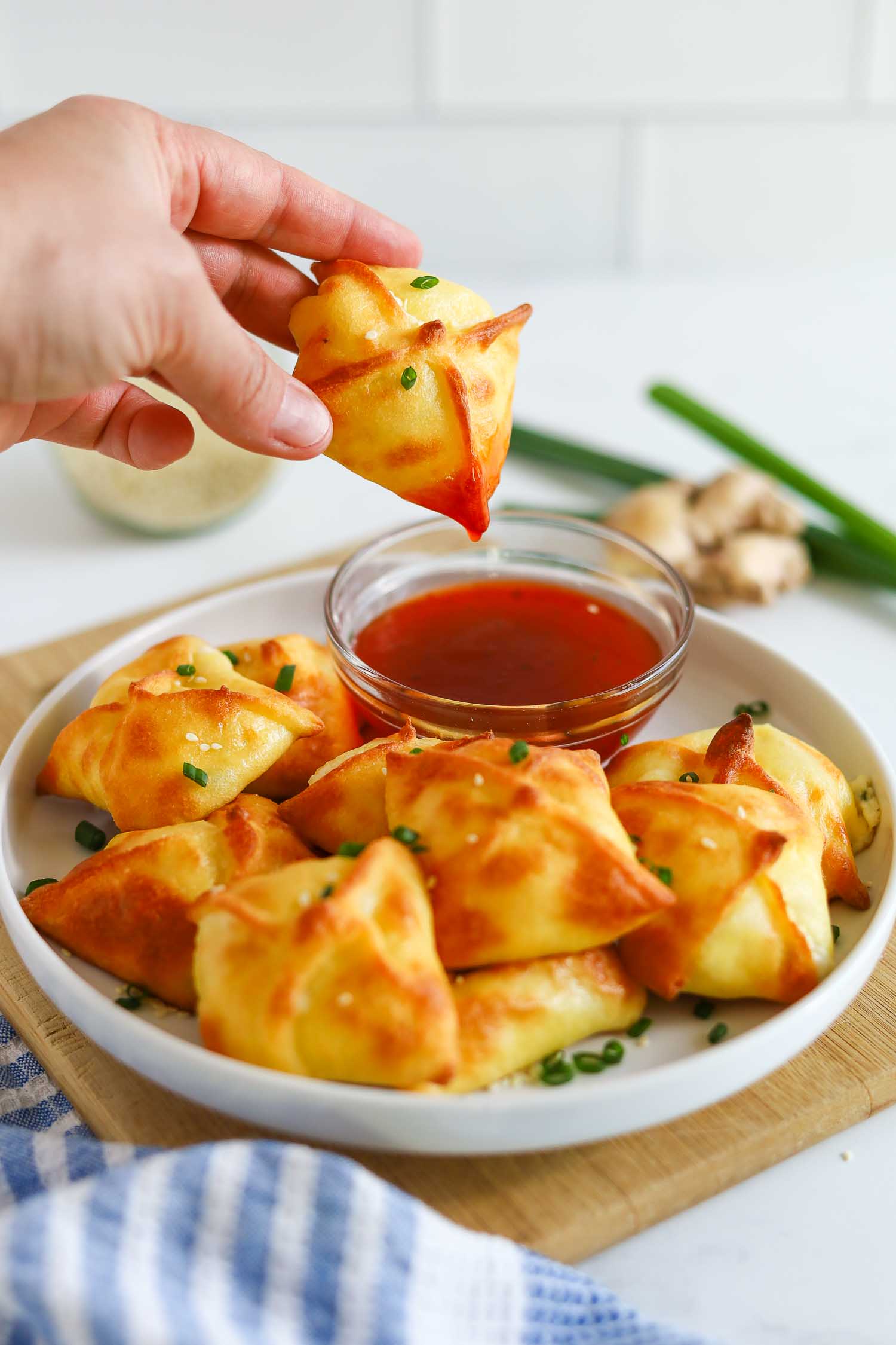 dipping crab rangoons into sweet and sour sauce 