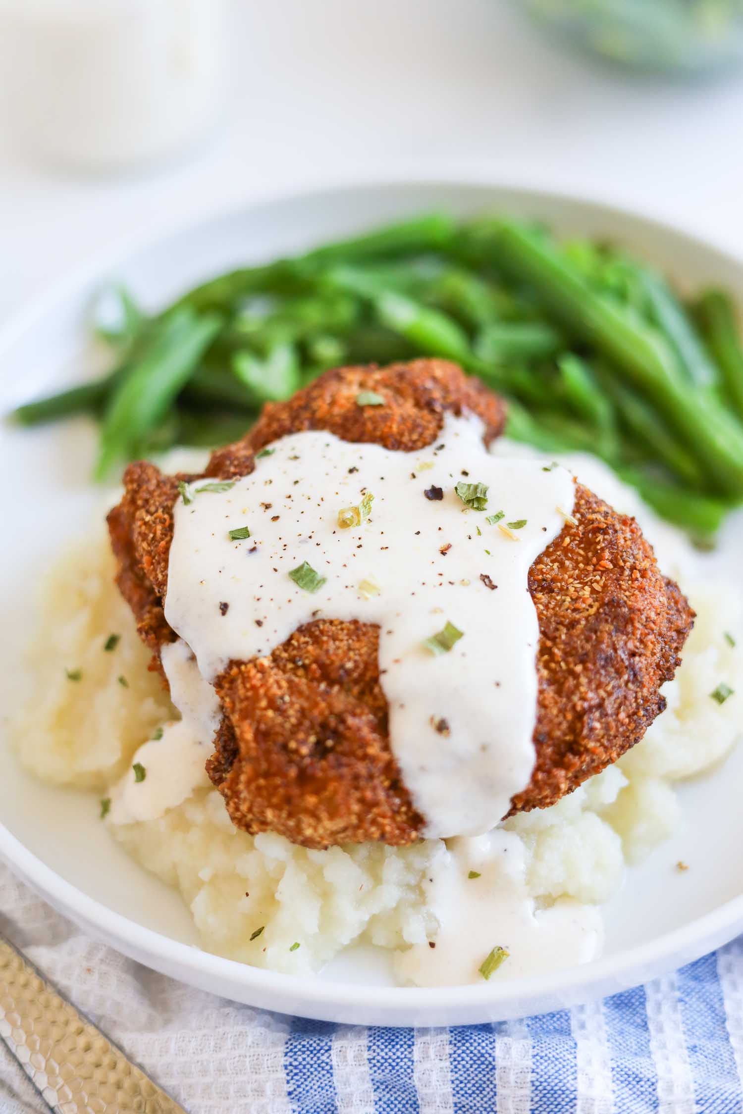 Keto chicken fried steak with mashed cauliflower and green beans on a plate 