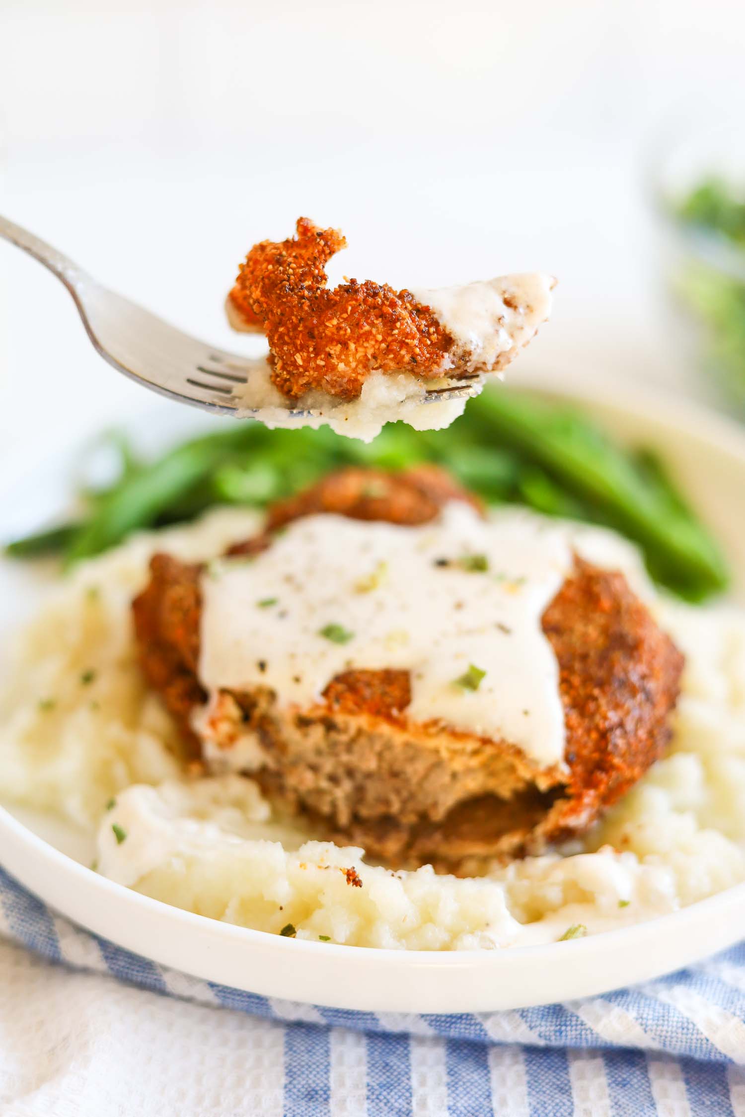 Cutting a bite from chicken fried steak with white gravy 