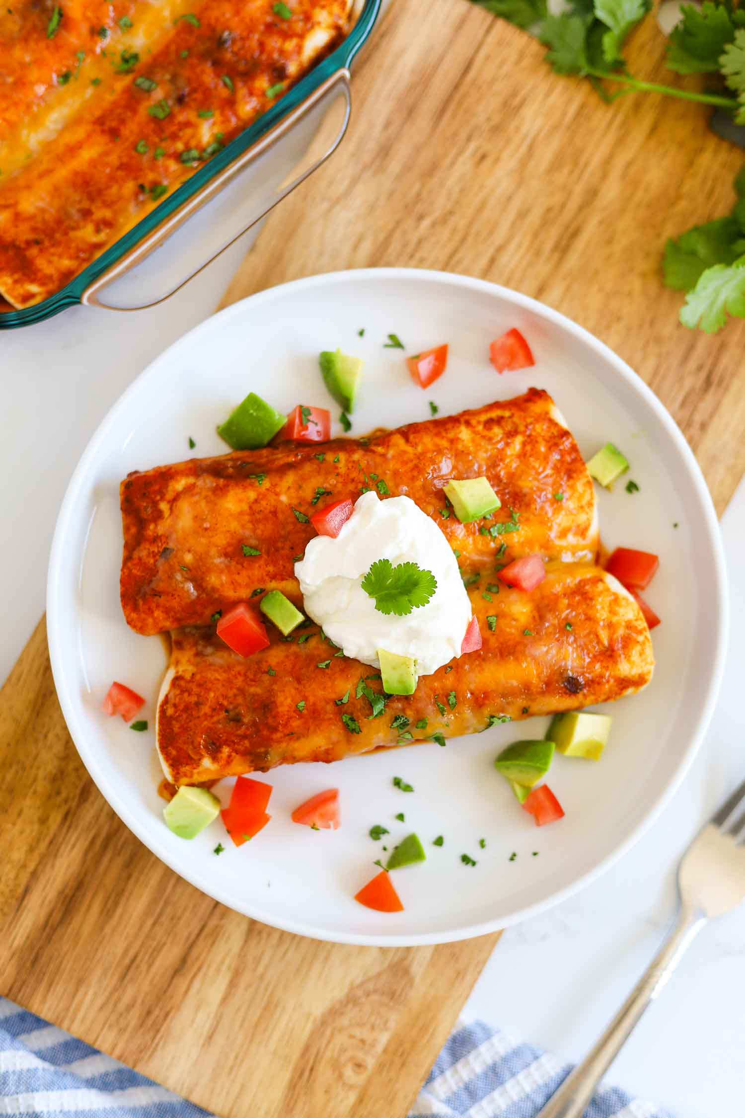 Overhead shot of keto chicken enchilada on a plate with sour cream and avocado pieces 