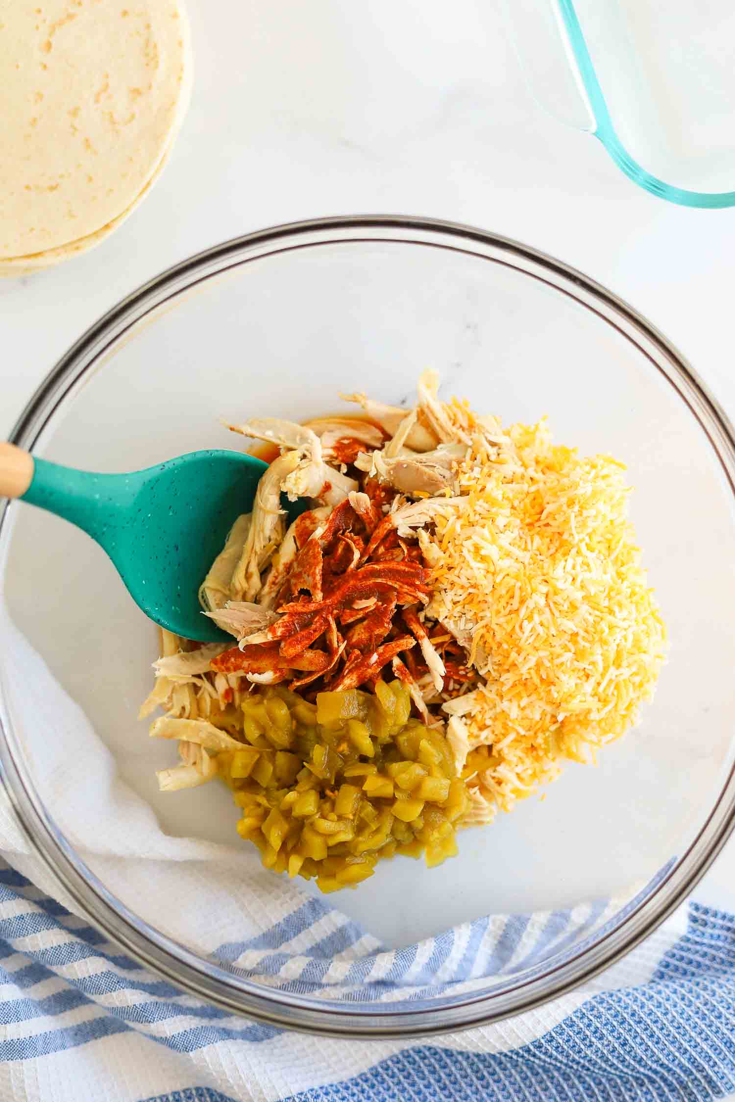 mixing together shredded chicken with green chili and enchilada sauce. 