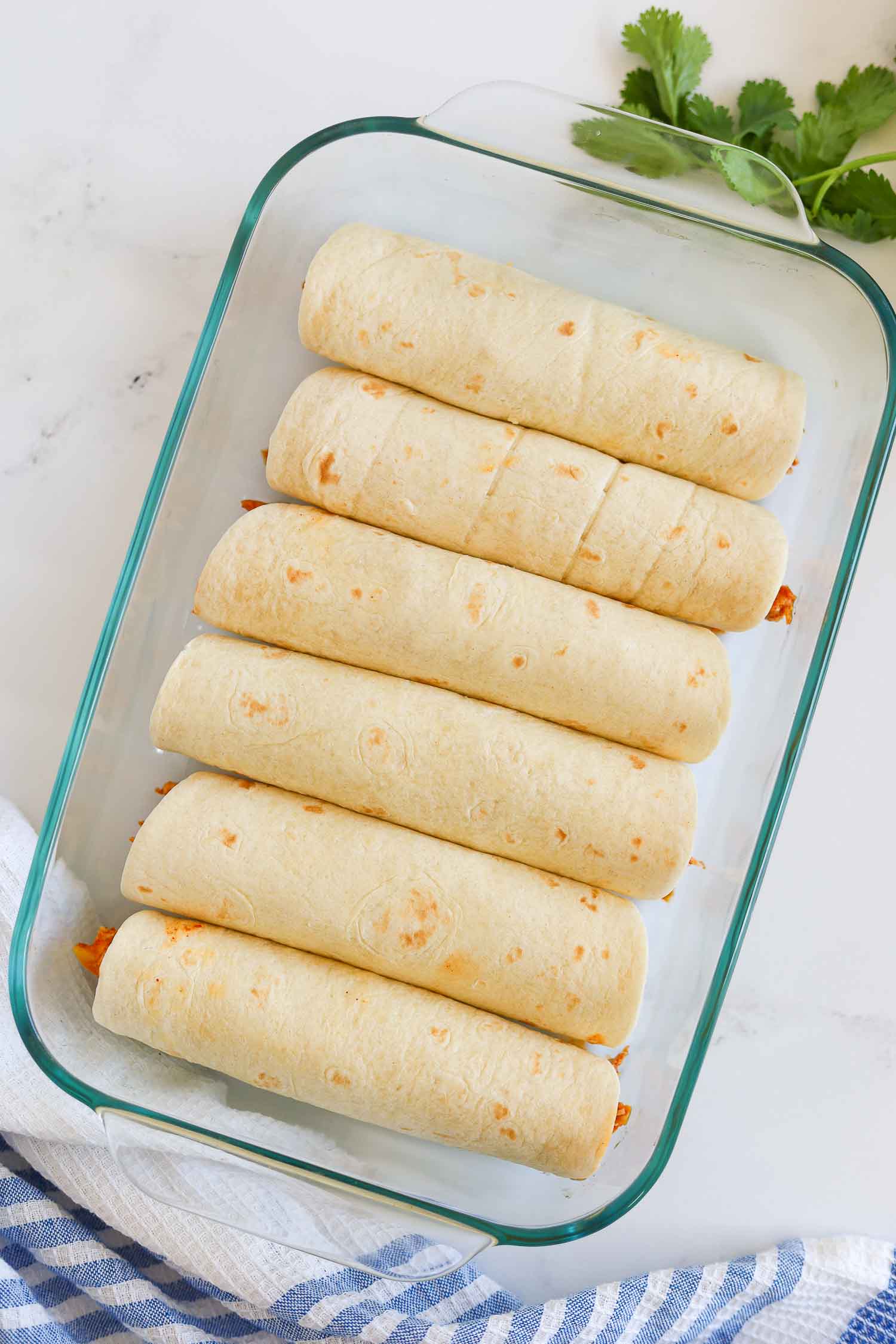 rolled chicken tortillas in a baking glass dish 