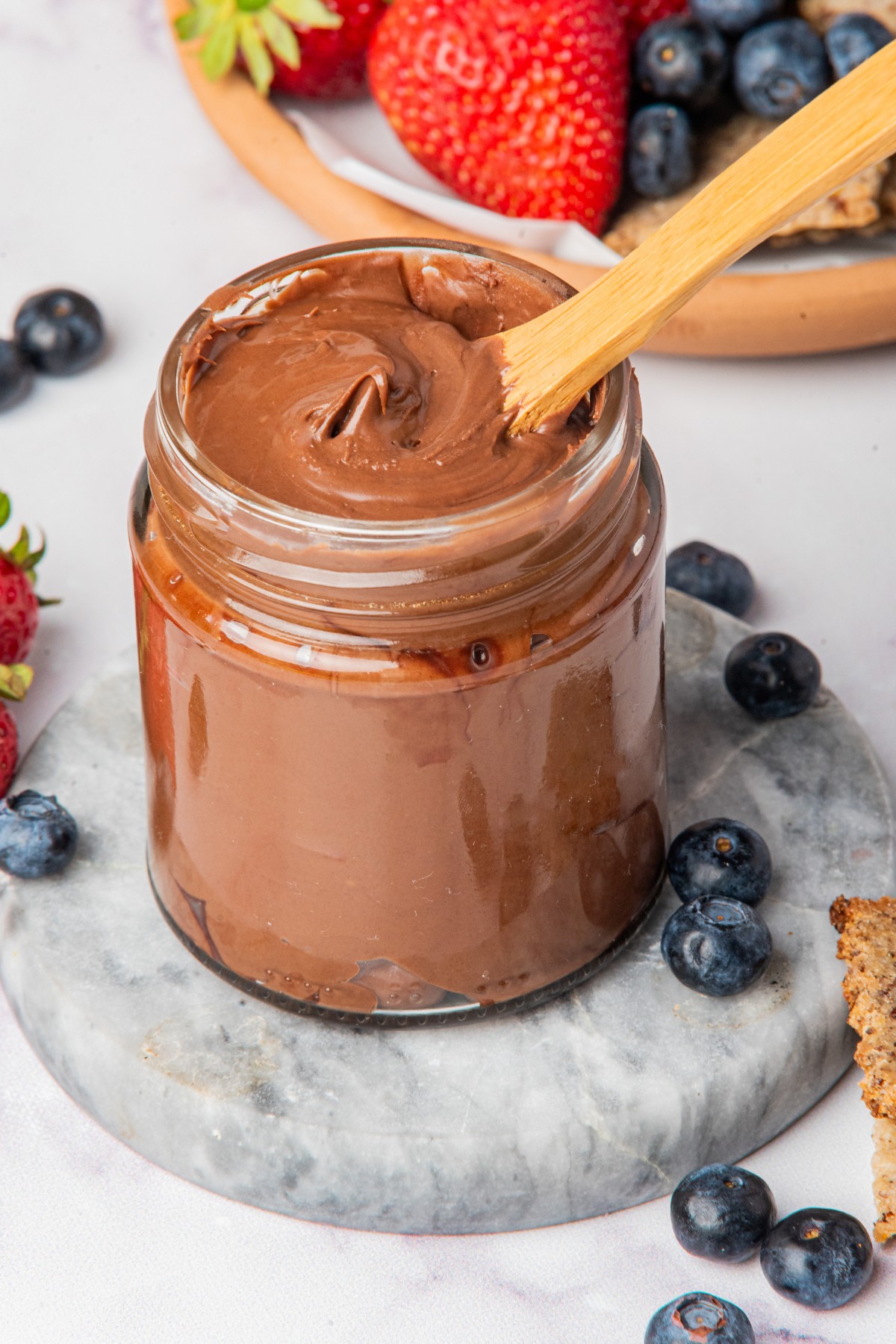 sugar free nutella chocolate in a jar with a spoon and berries