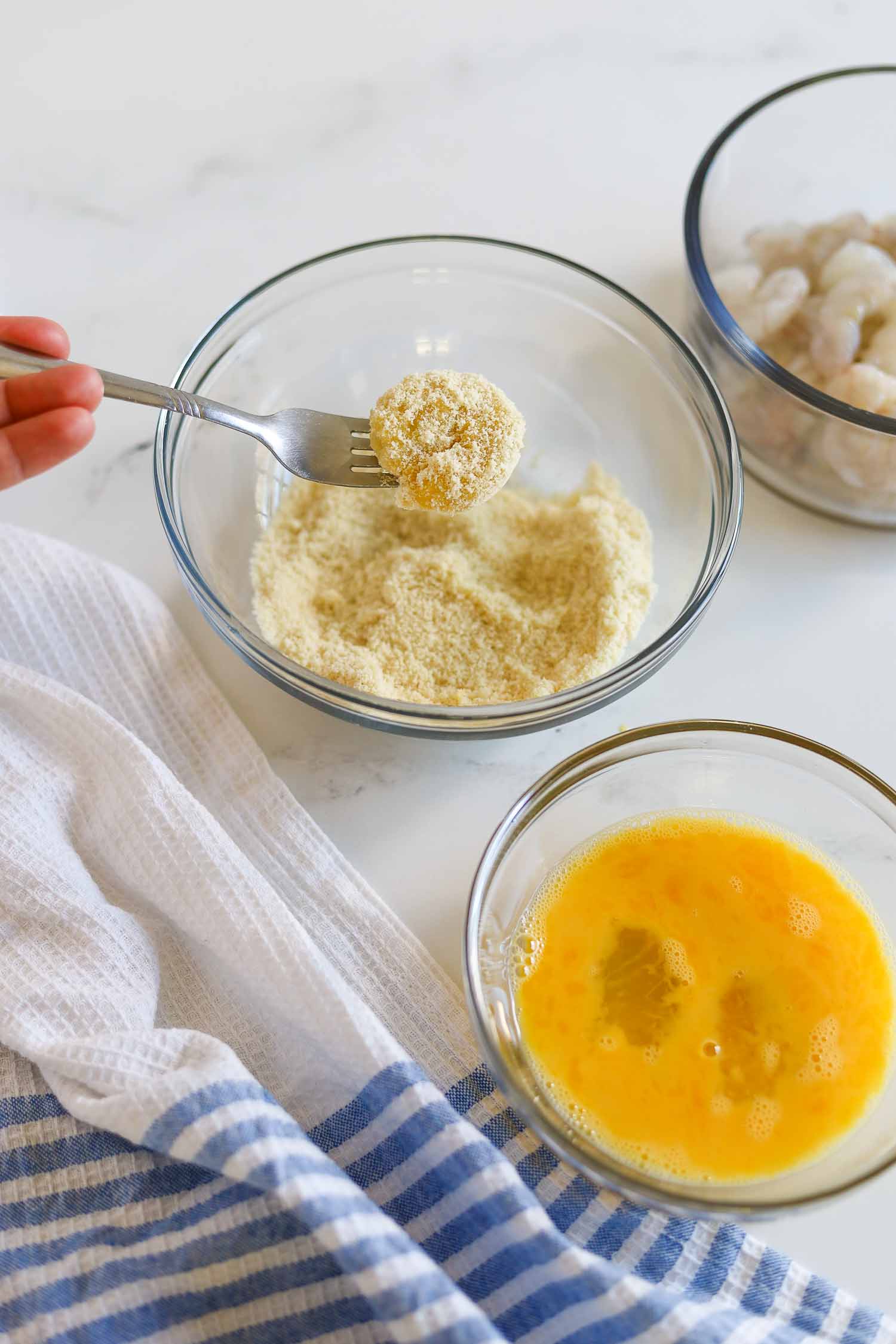 dredging shrimp in egg wash and almond flour bread crumbs 