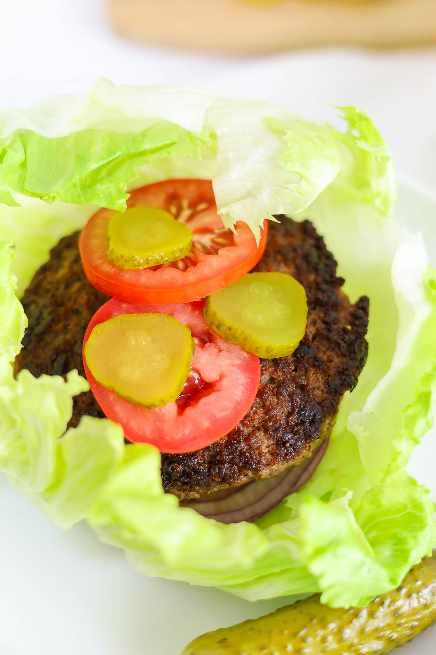 lettuce wrapped lucy cheese burger with tomatoes and pickles 