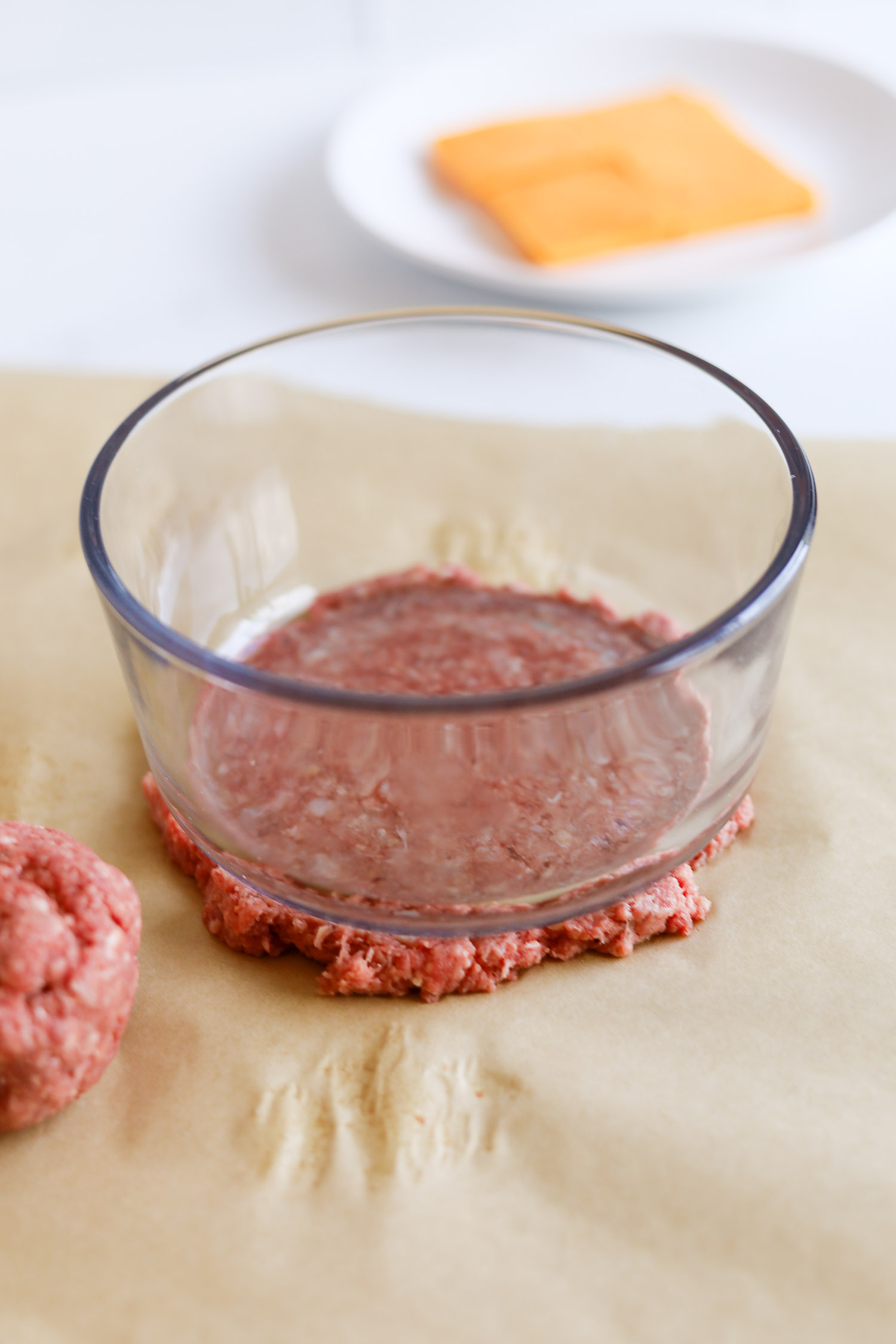 smashing ground beef patty with a glass container 