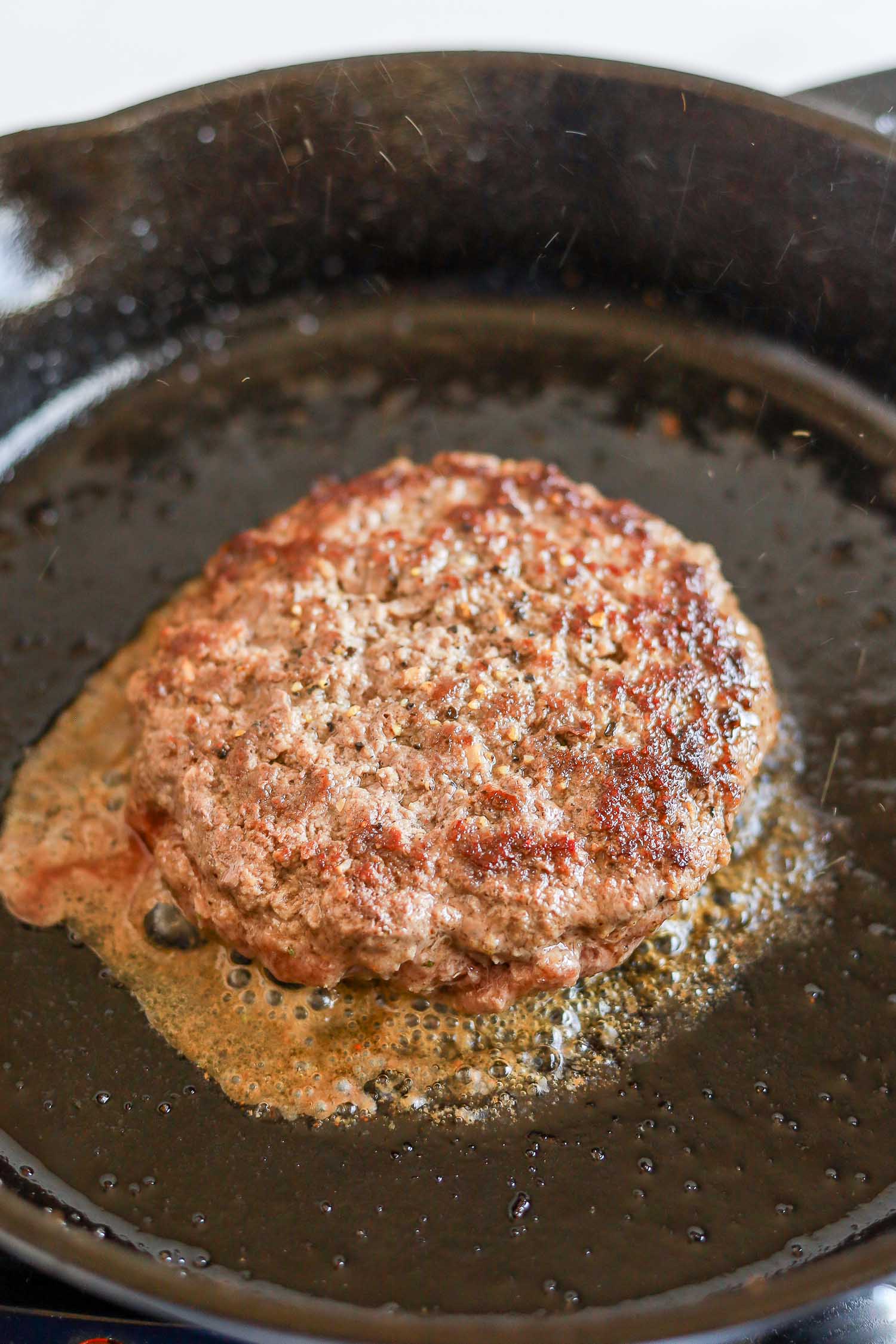 searing burger patty in a cast iron skillet 