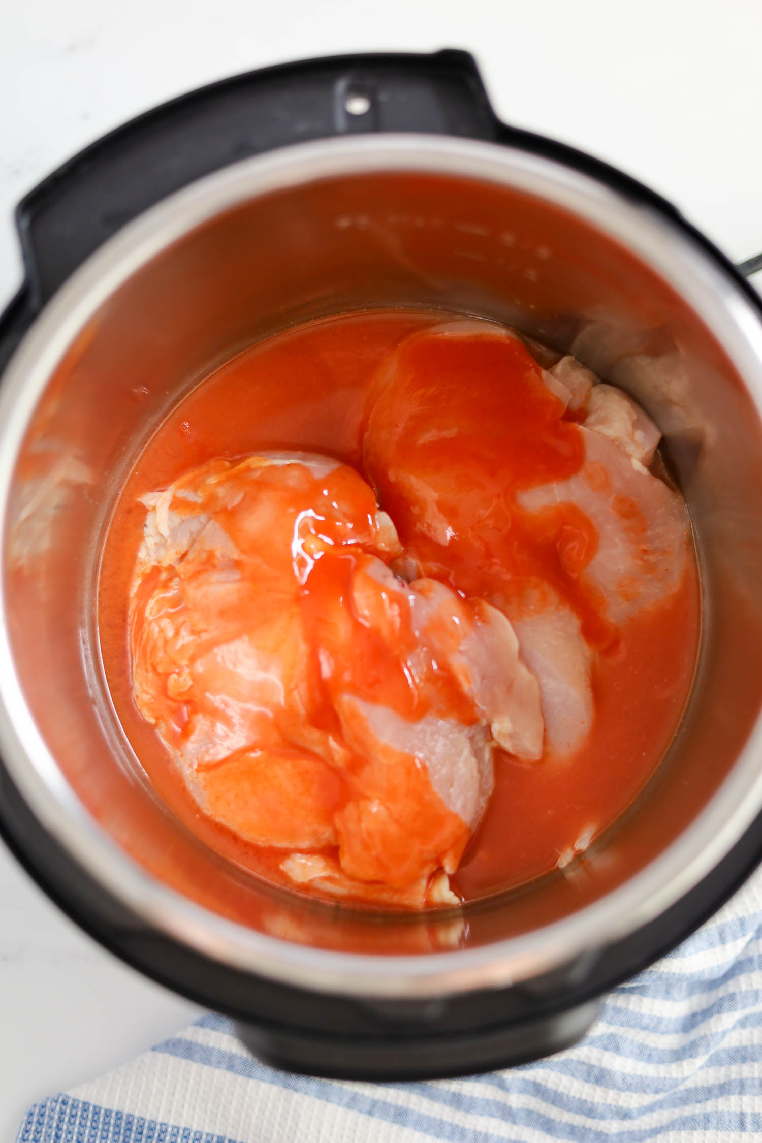 adding raw chicken breasts and hot sauce to instant pot 