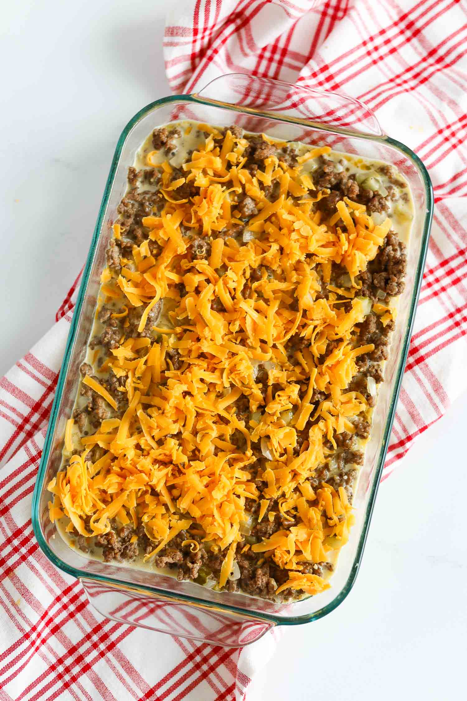 adding sharp cheddar cheese over the ground beef casserole