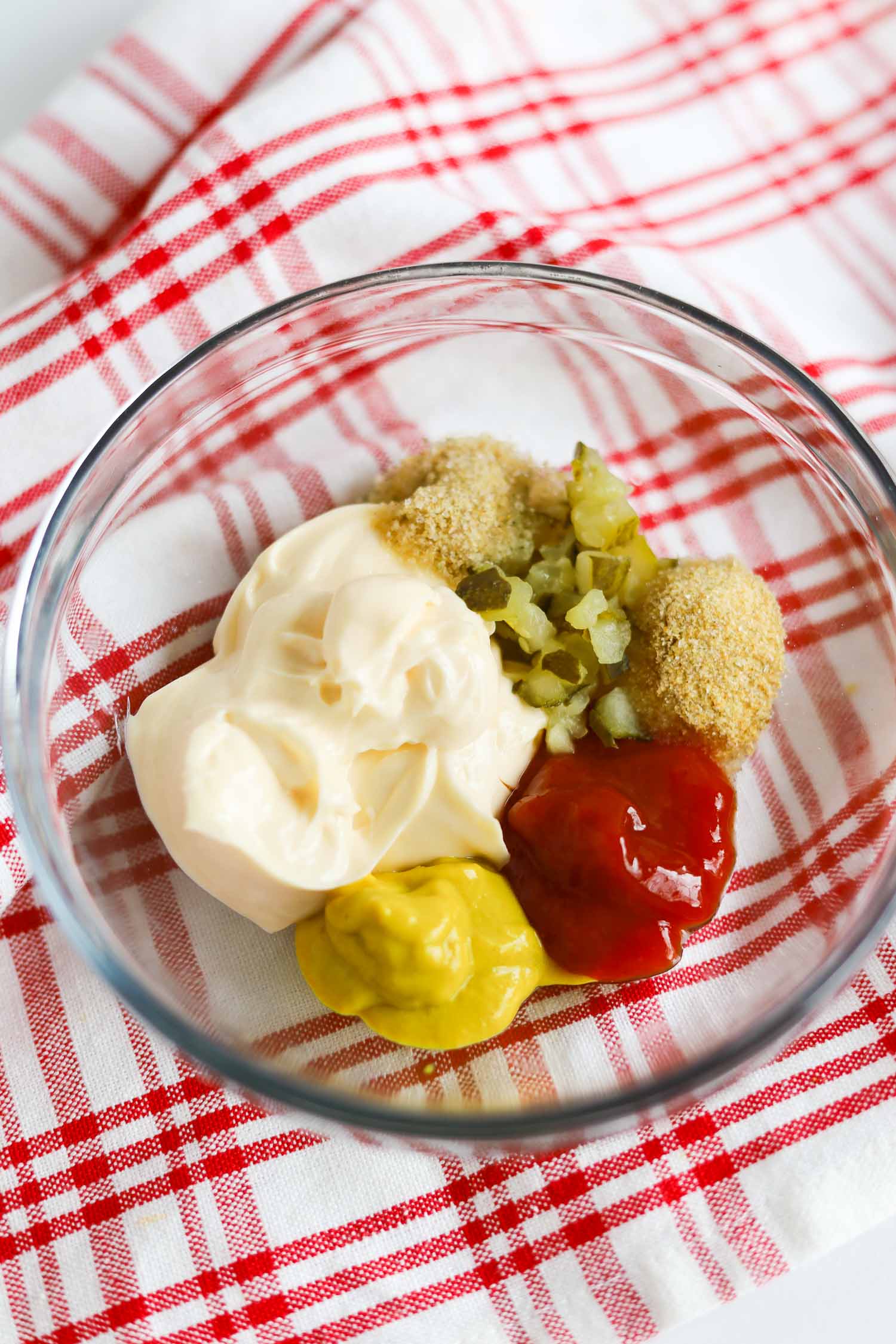 adding all of the ingredients to make burger sauce in a bowl 