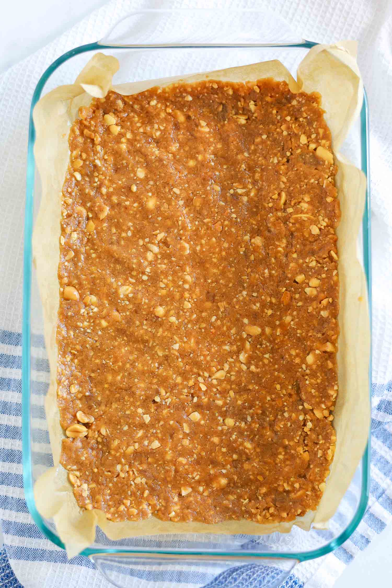 adding peanut nougat to glass container with parchment paper 