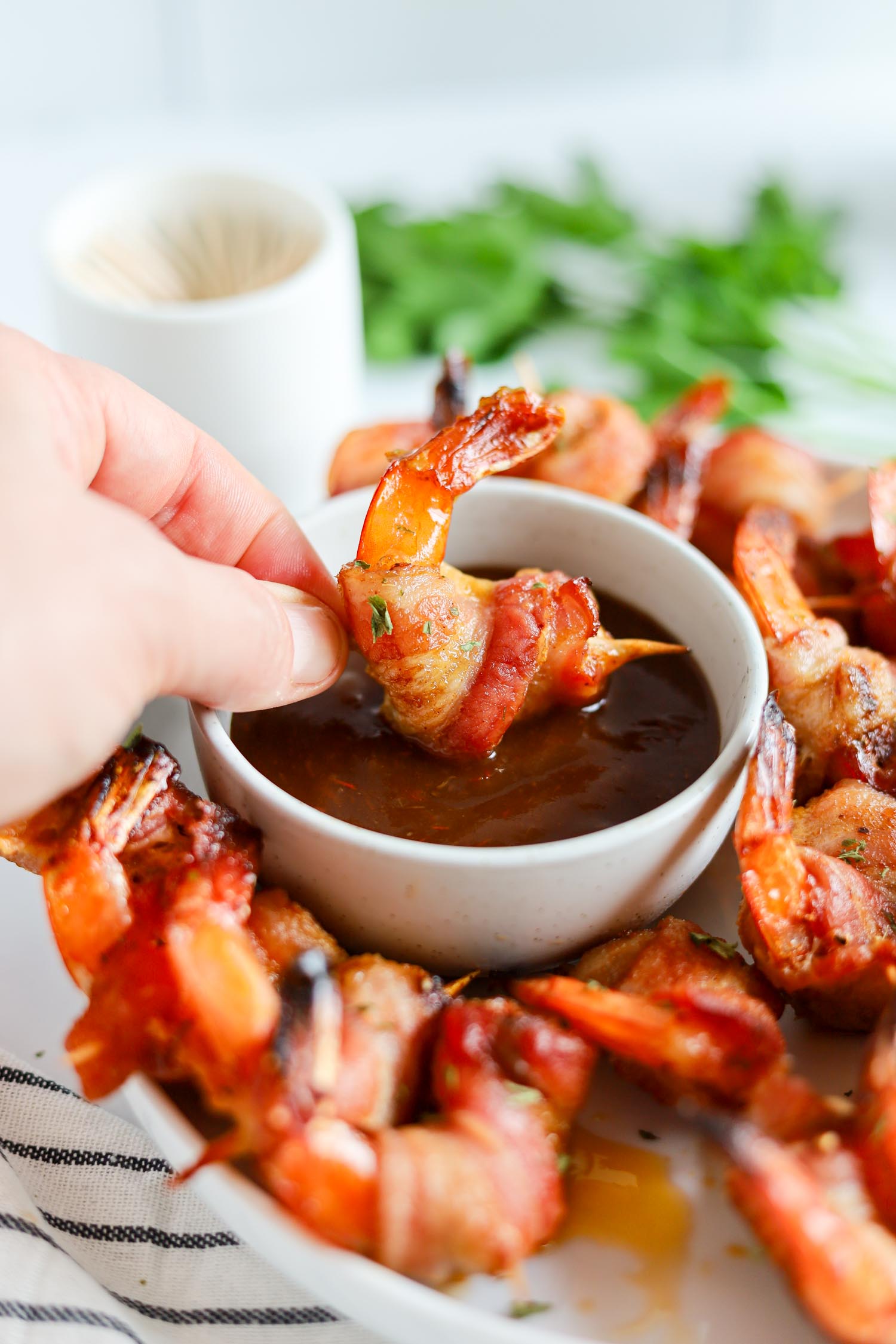 bacon wrapped shrimp dipped into BBQ sauce