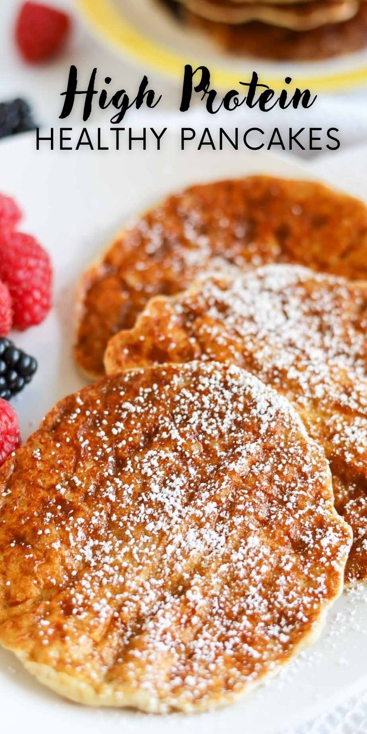 Fluffy low carb pancakes stacked high with raspberries and syrup drizzle and powder sugar