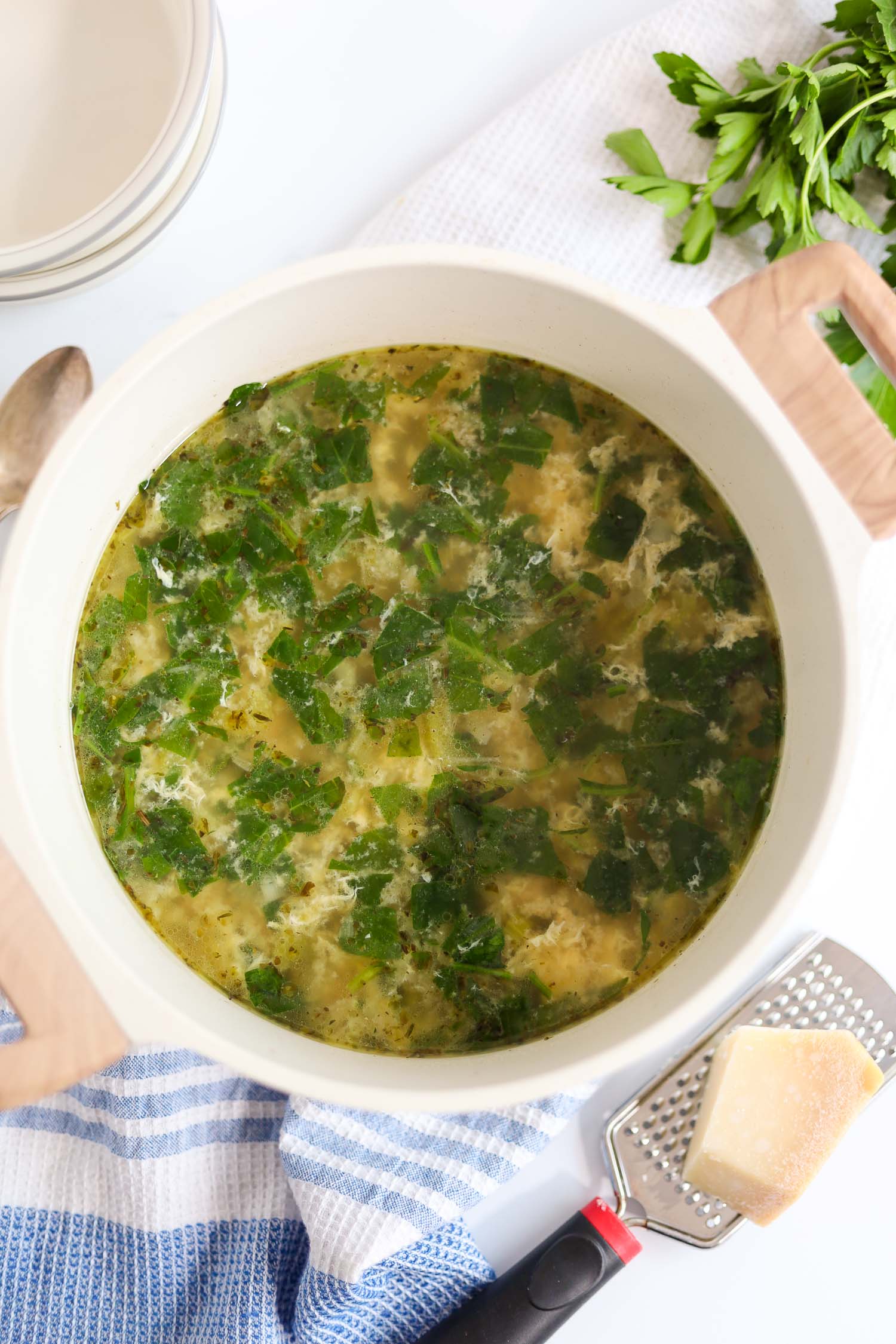 Adding raw spinach and whisked eggs to the soup broth